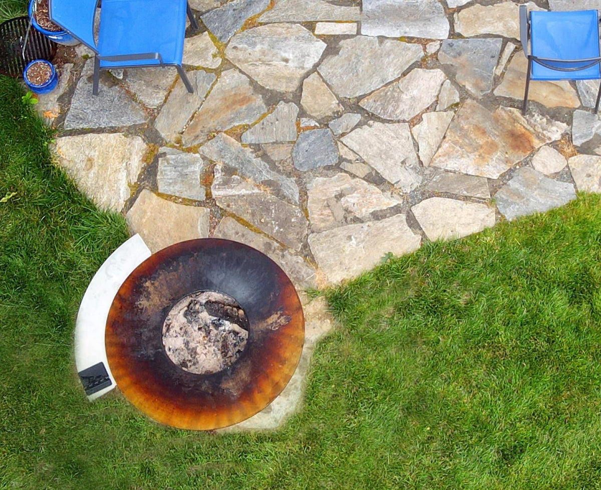 Round rusted steel fire pit bowl on grass