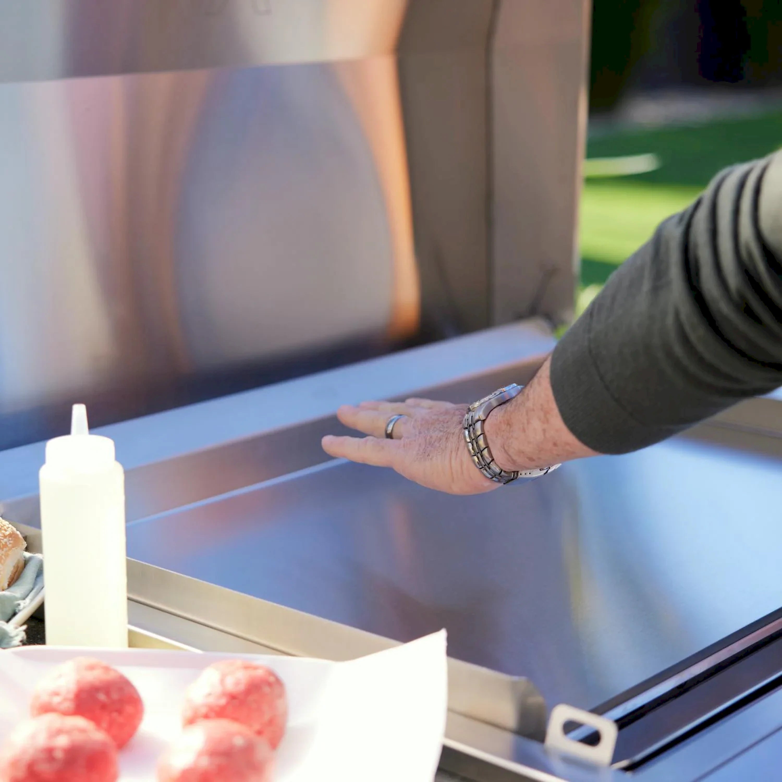 Stainless griddle side area with hand adjusting controls near bottle