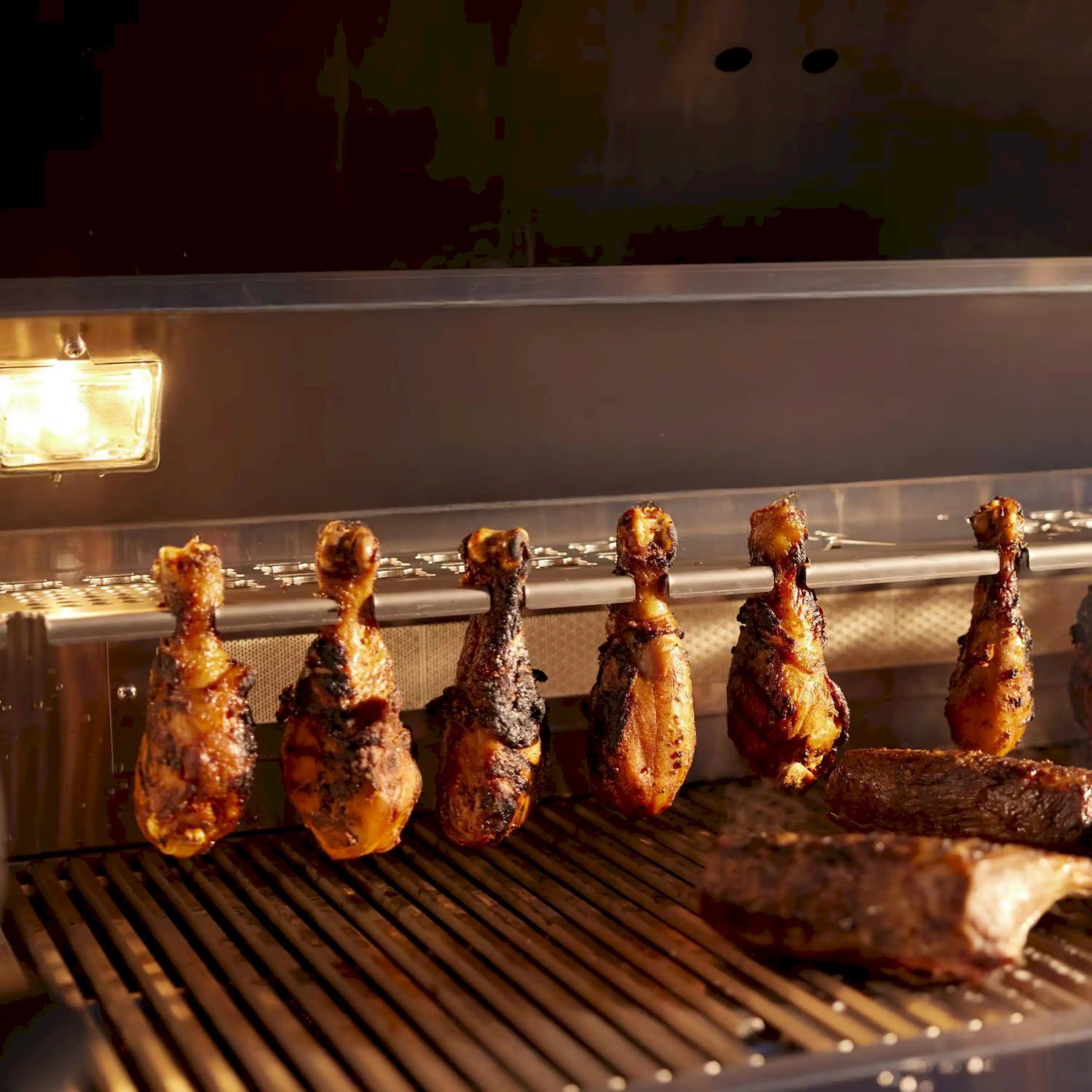 Gas grill cooking grates with roasted chicken pieces on skewers
