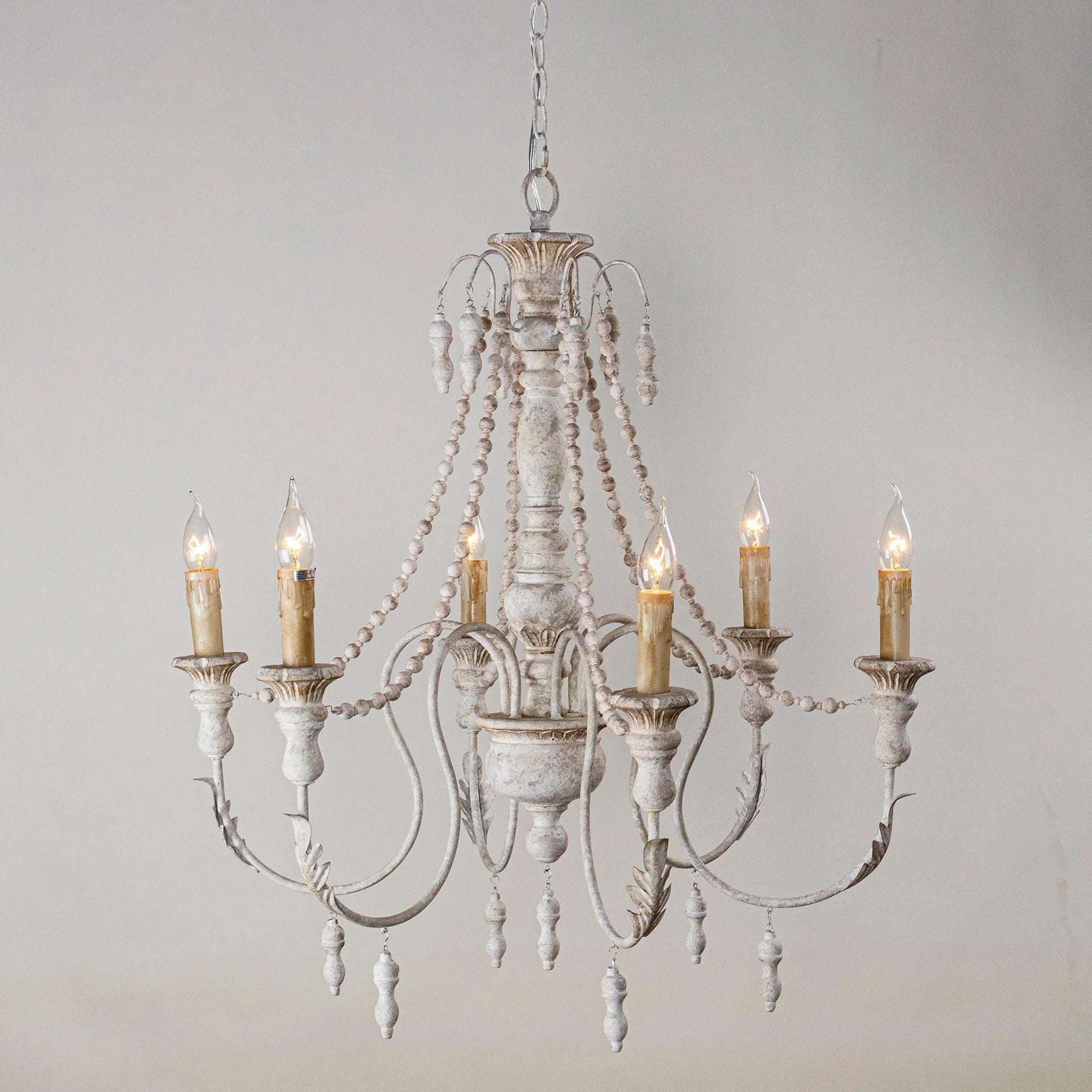 White six-light chandelier with central scrollwork, bead drops, and curved candle arms