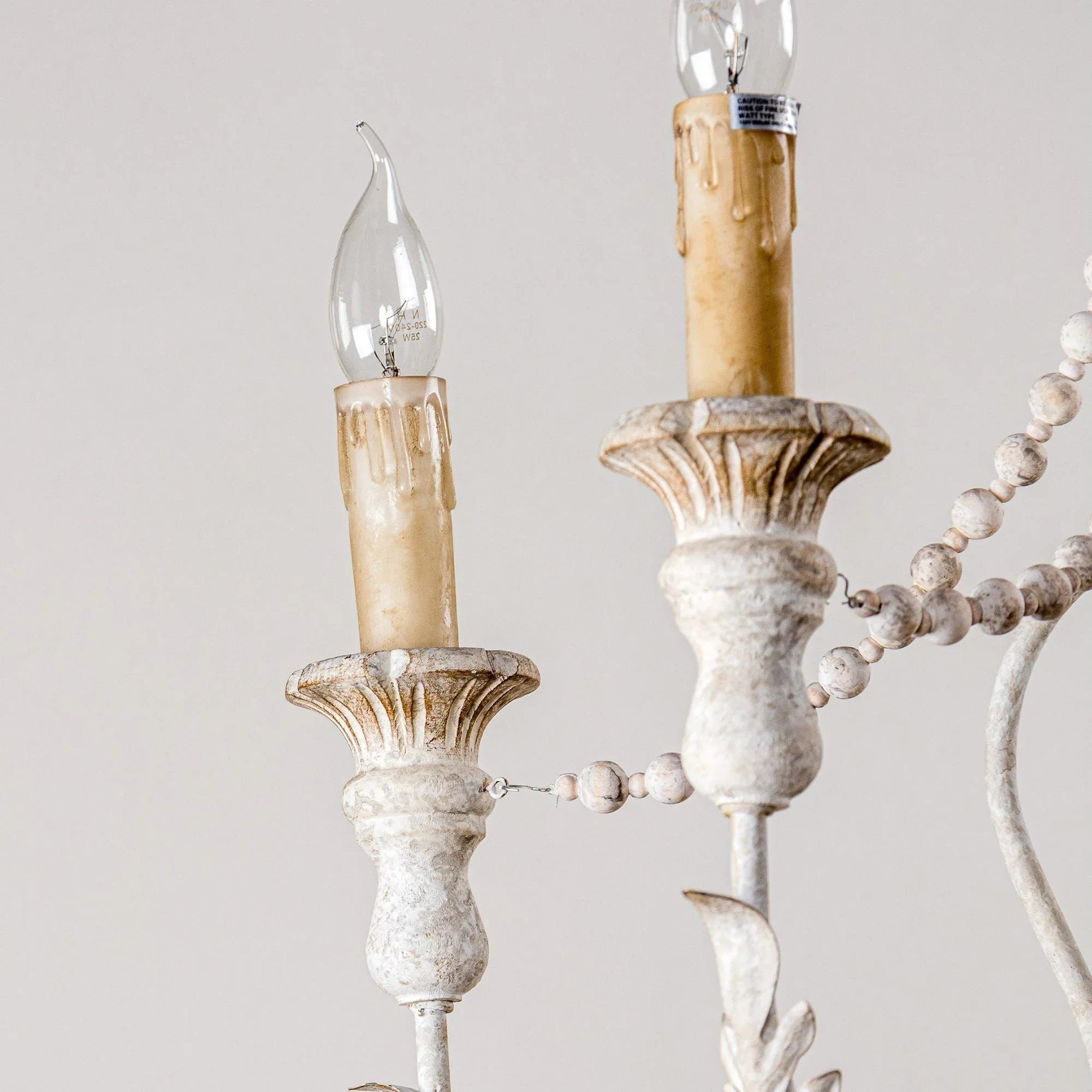 White and distressed metal chandelier arms with clear candle bulbs and bead detailing