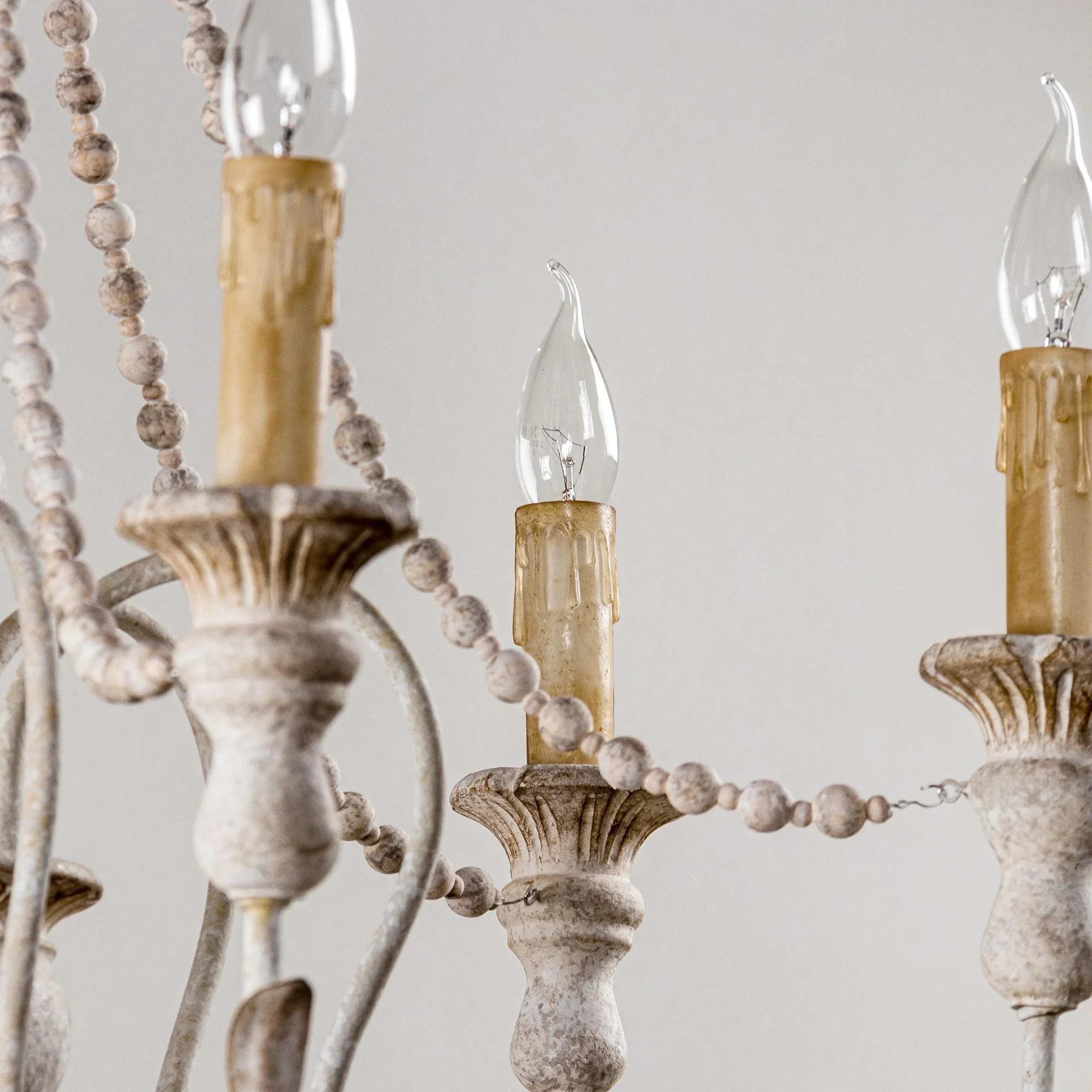 Curved candle-arm chandelier with white candlesticks and hanging bead accents