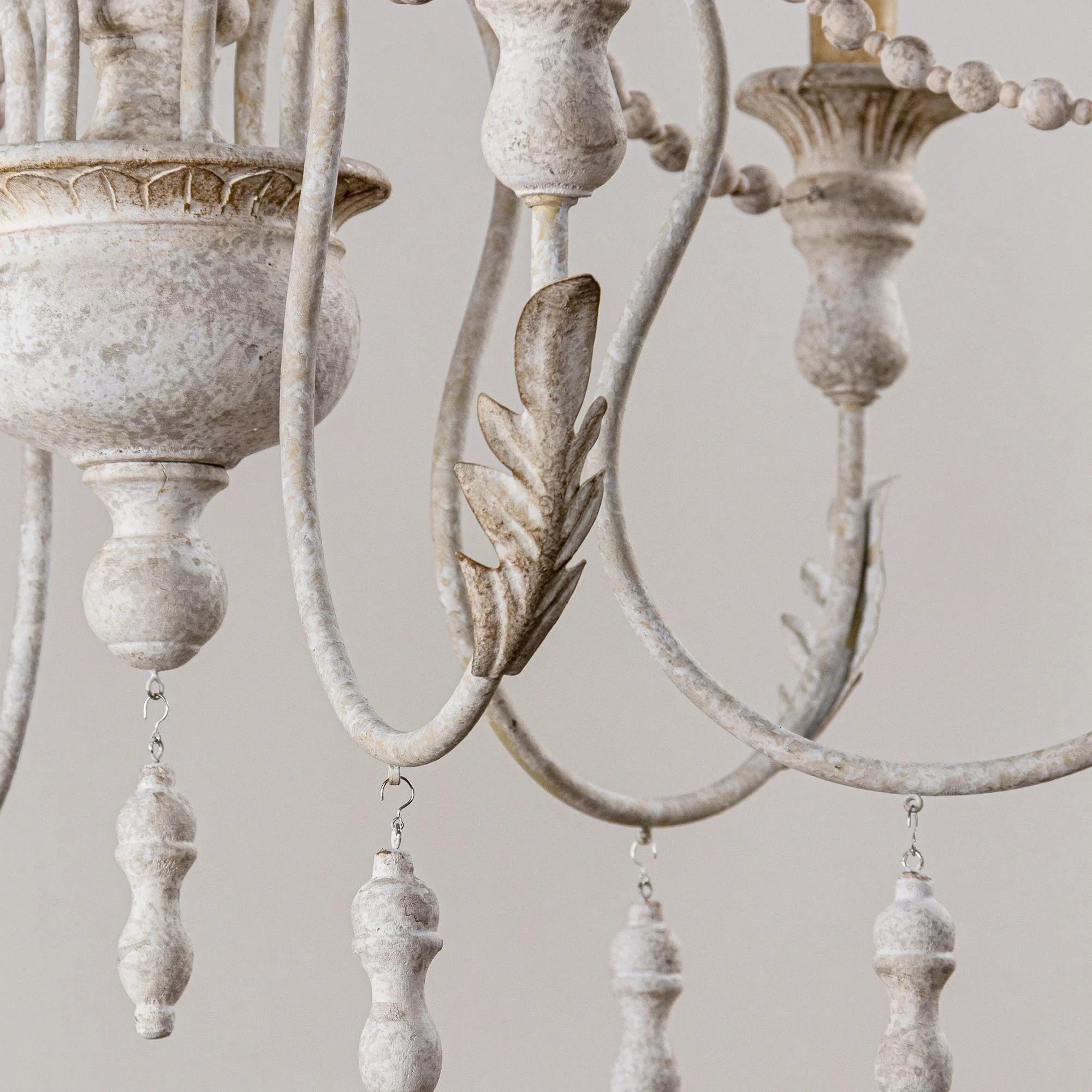 Close view of chandelier curved arms, bead strands, and white candlestick sockets