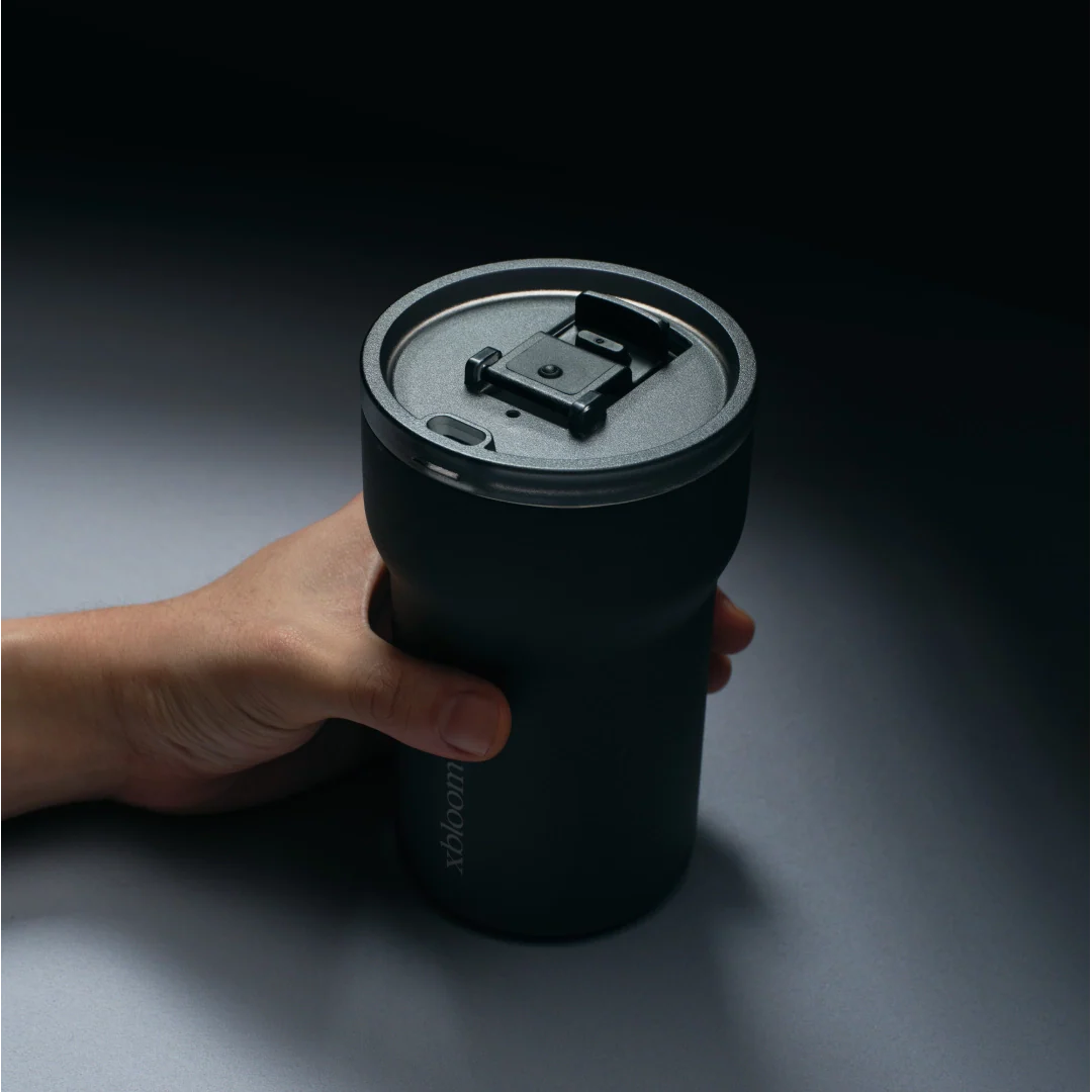 Charcoal black xBloom passenger tumbler held in hand, open lid
