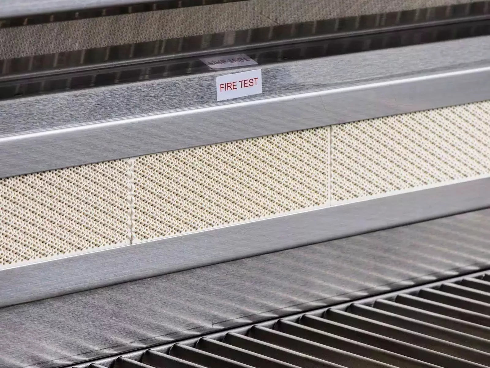 Built-in gas grill front panel with perforated heat shield and “FIRE TEST” label