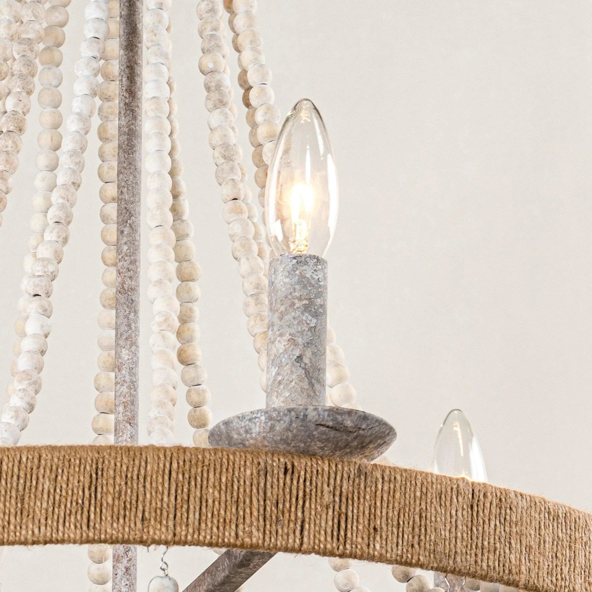Detail of white beaded cords and gray candle-holder sockets on a round chandelier ring
