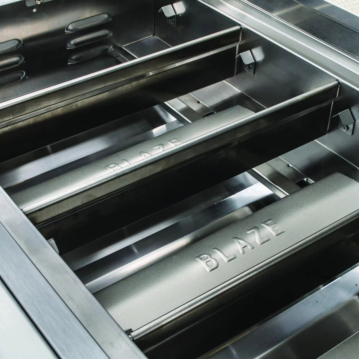 Stainless grill firebox with grates and BLZ branding on the interior base