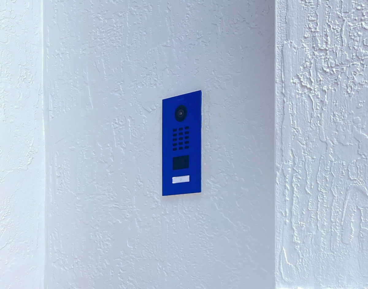 Ultramarine blue wall-mounted video door station with camera and keypad panel