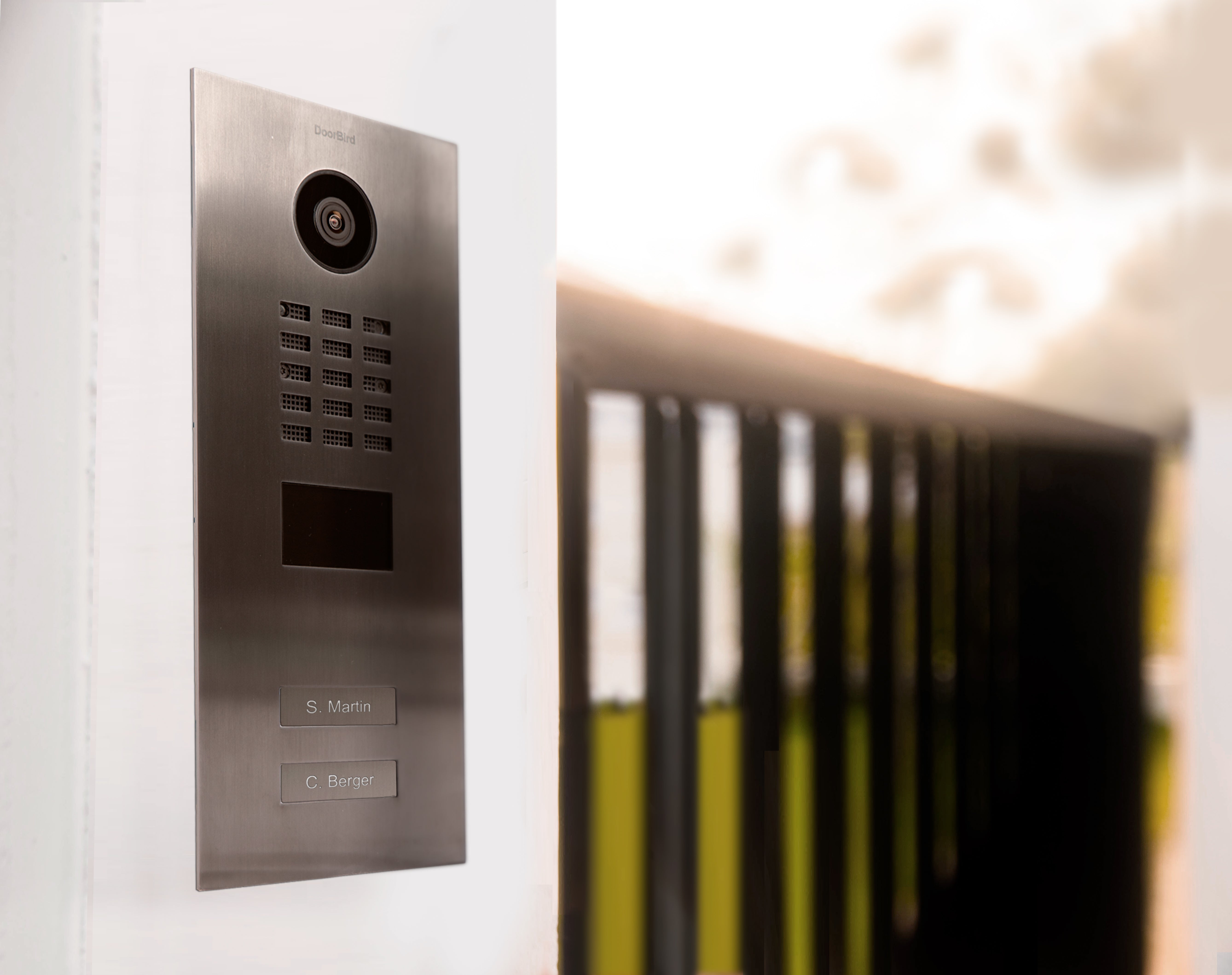 DoorBird titanium video door station with lens camera and speaker grille, angled on wall