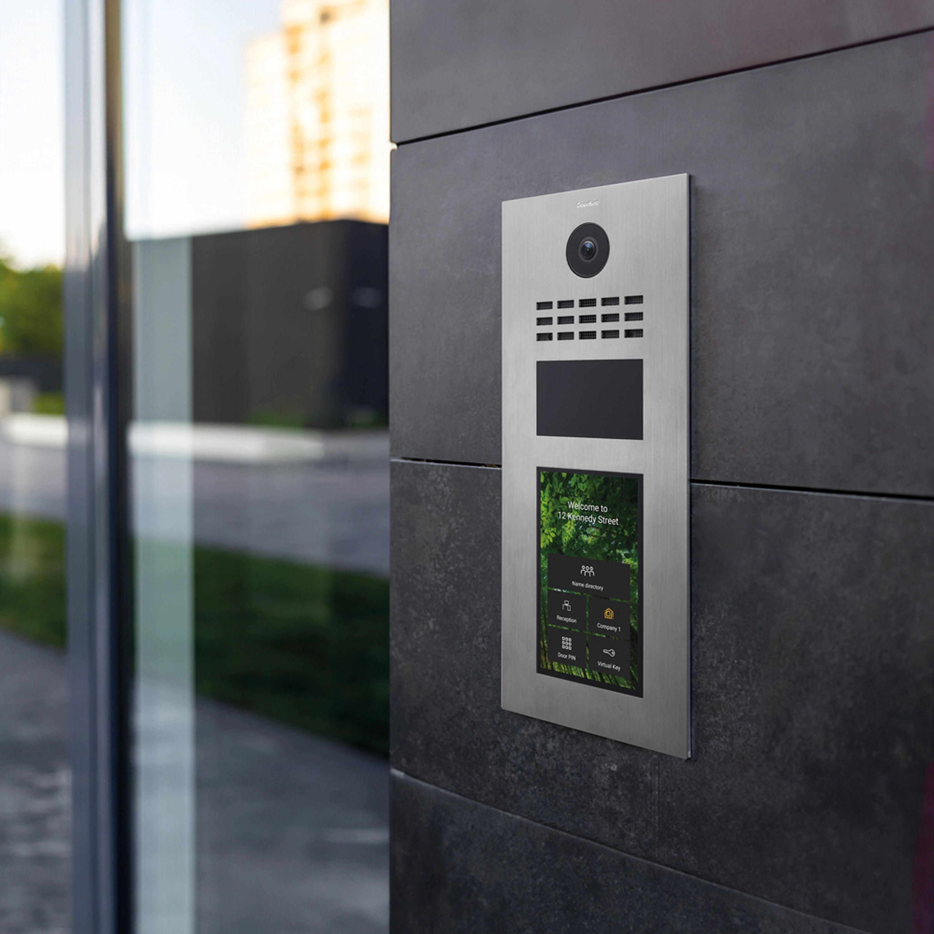 DoorBird stainless steel IP video intercom mounted on wall with lit display