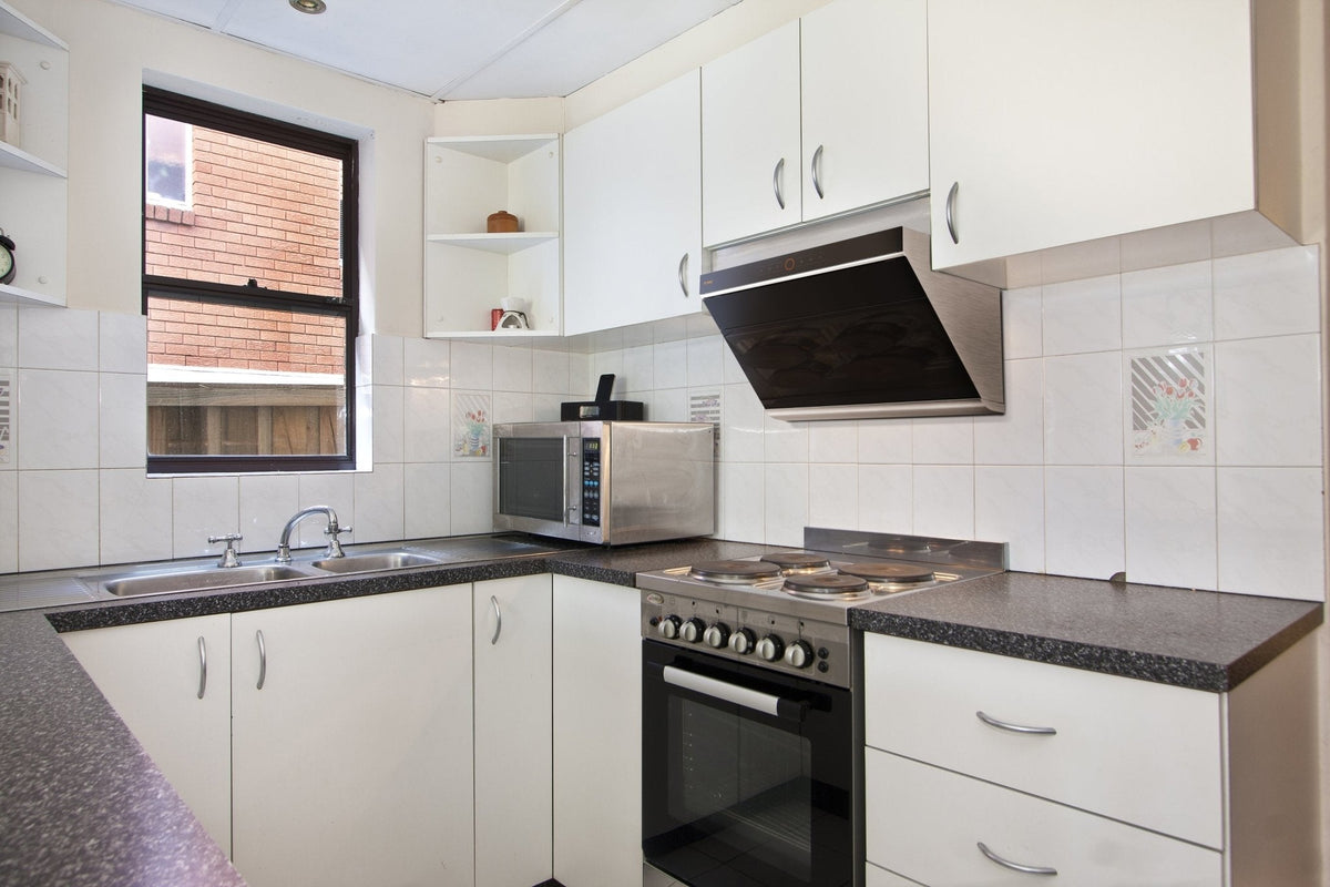 Black slant range hood with decorative vent panel and stainless control area