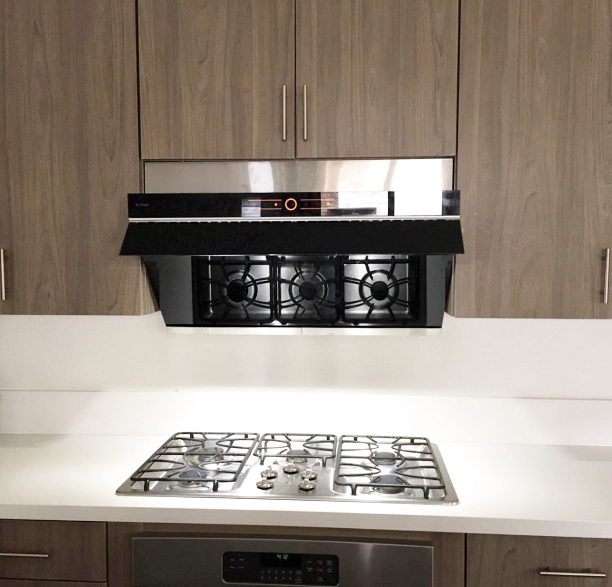 Black decorative vent plate installed over cooktop, slim front with narrow slots