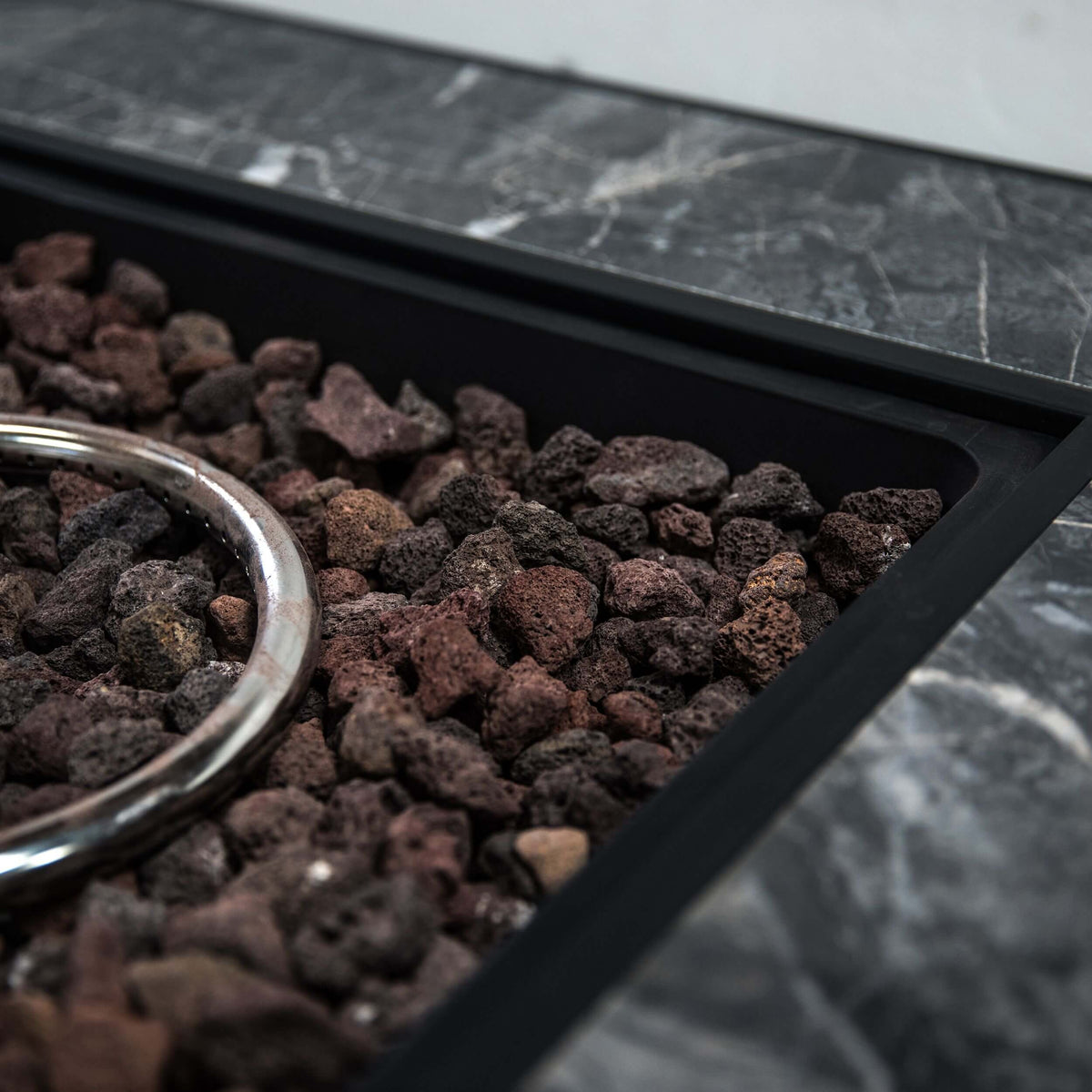 Side view of lava rocks inside the firepit bowl with a curved metal ring handle