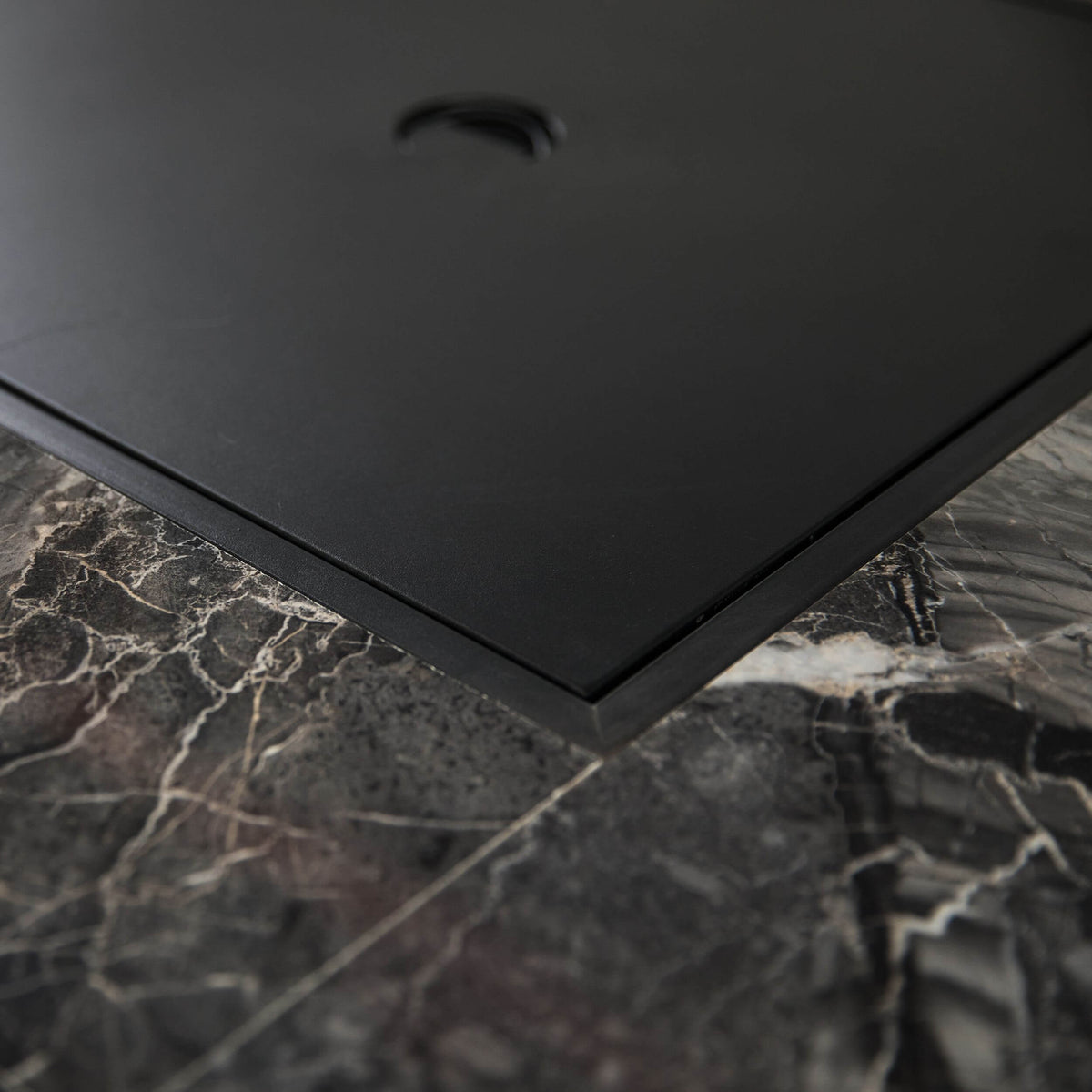 Corner detail of the firepit table: black frame border on gray stone top