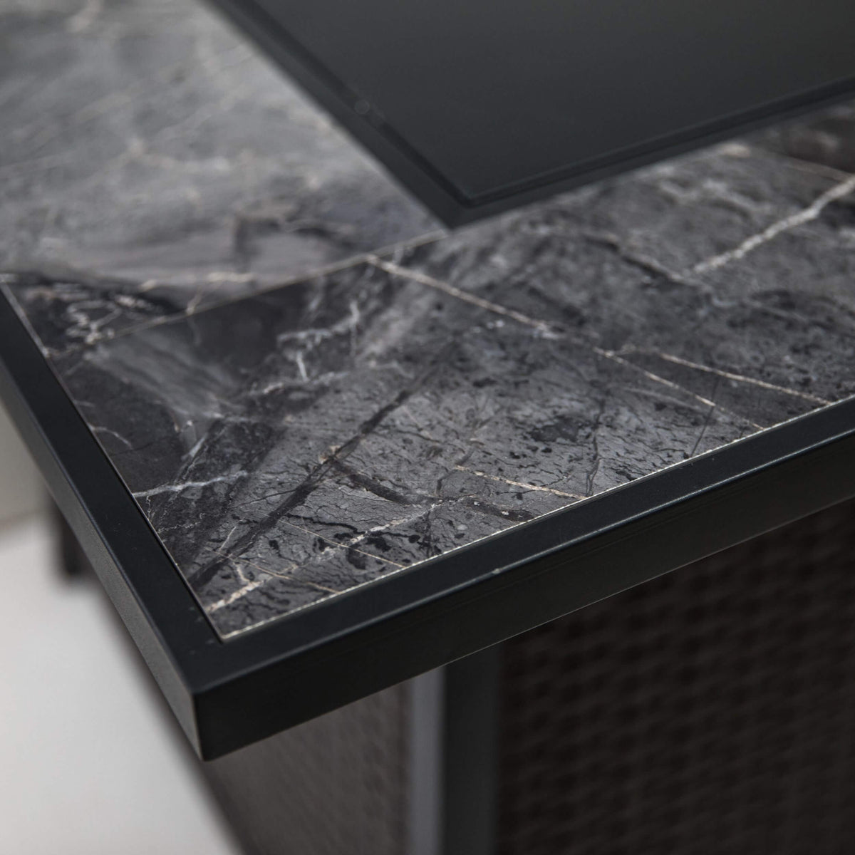 Bottom corner of the firepit table with gray stone top trim and dark frame edge