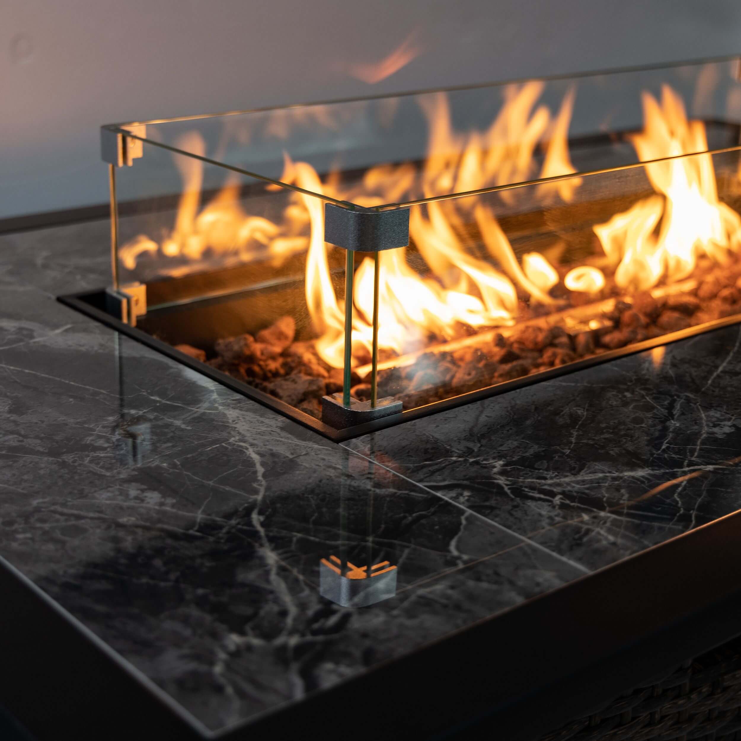Brown wicker propane gas fire pit with flame guard and glowing fuel bed
