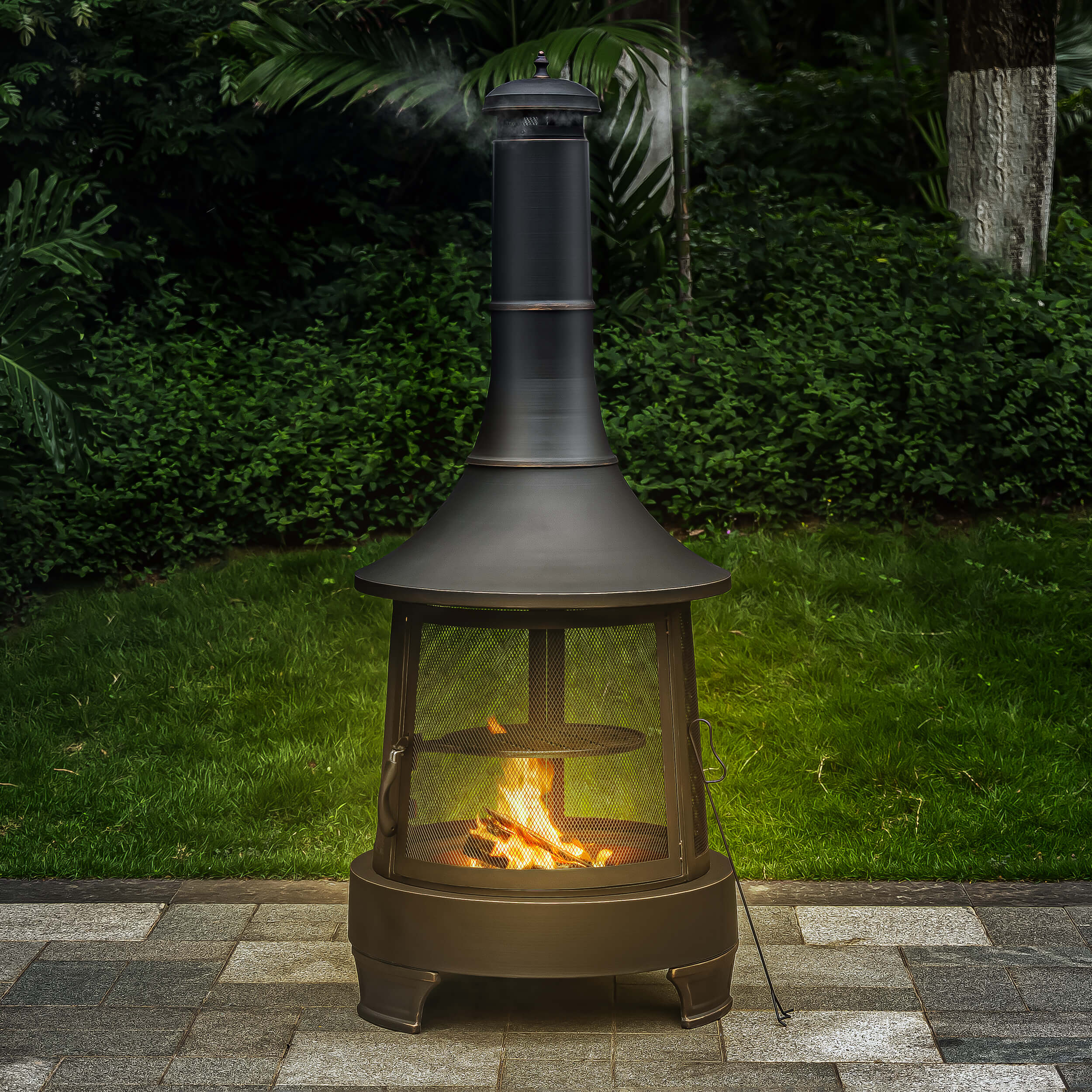 Chimney wood burner firepit with flames inside mesh door on patio stones