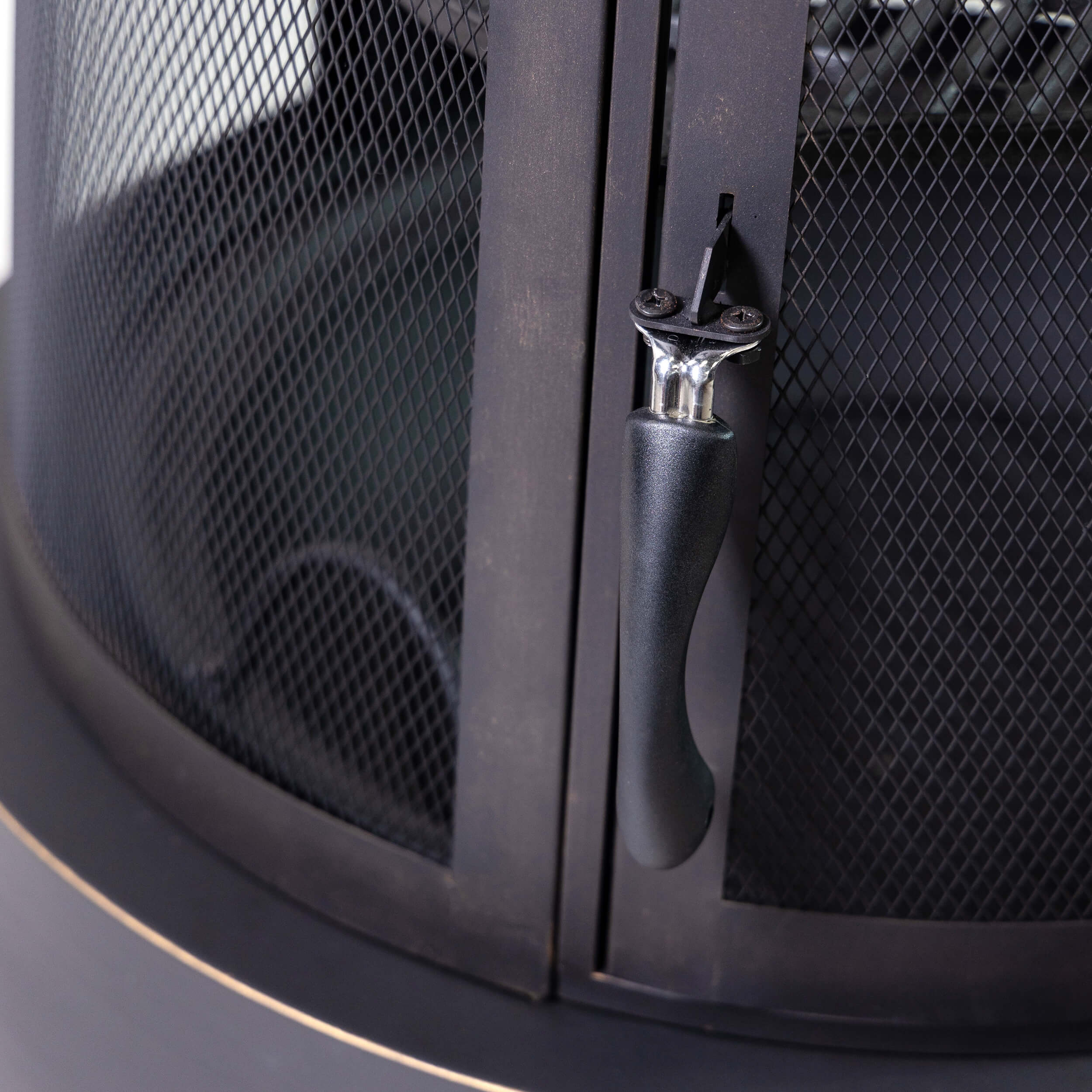 Close-up of firepit mesh door and curved handle latch in dark metal