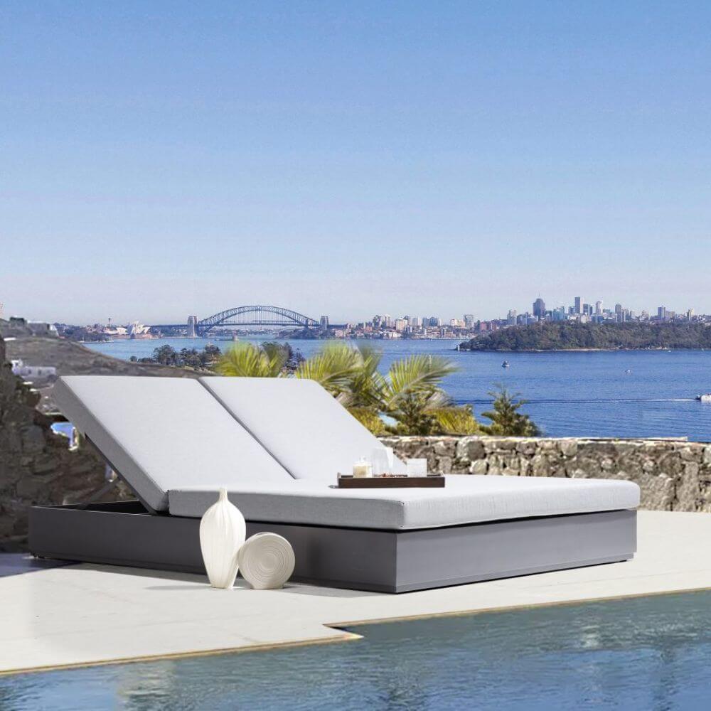 Gray outdoor patio daybed with dual cushions and dark base on patio setting