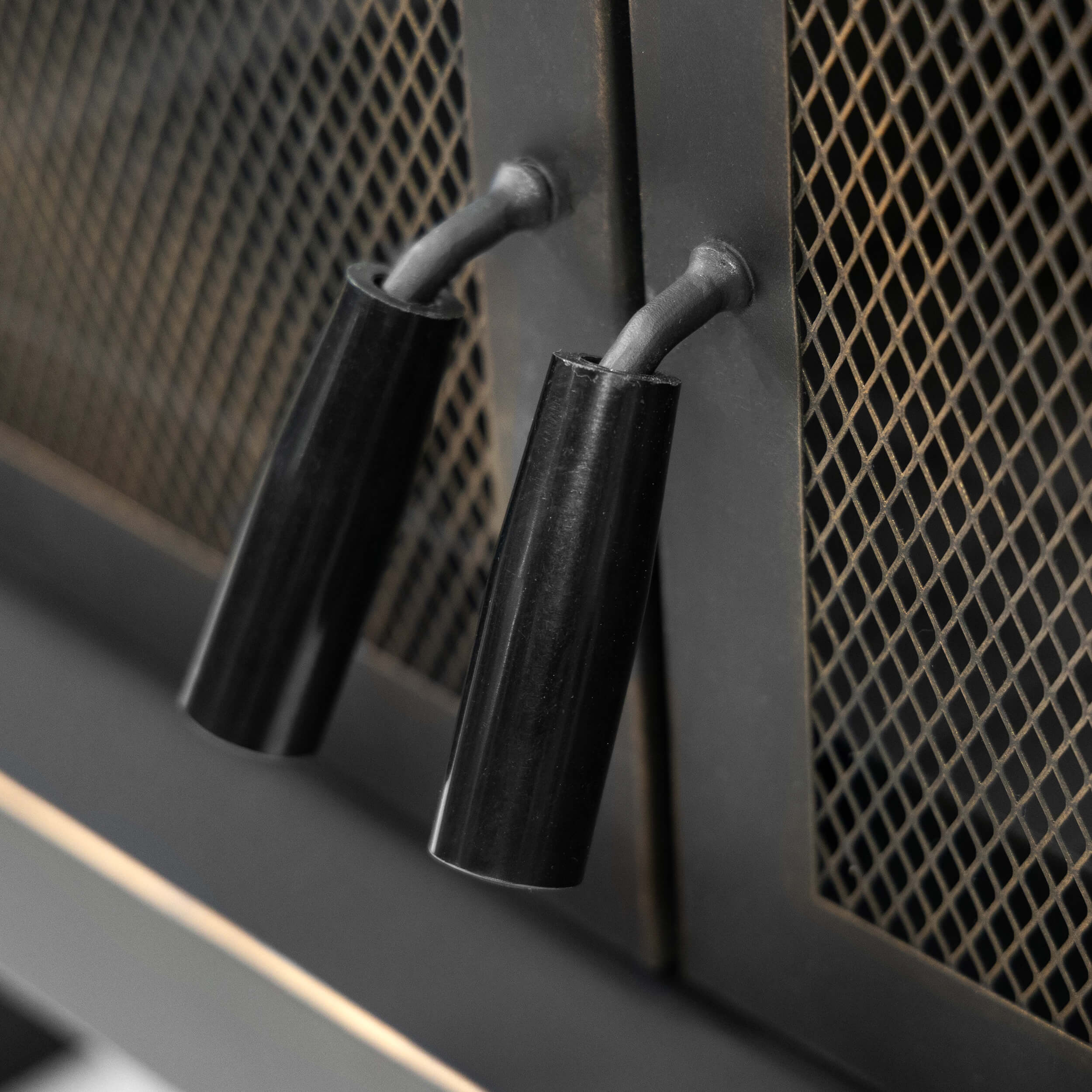 Detail of black metal stove tools hanging on the mesh door