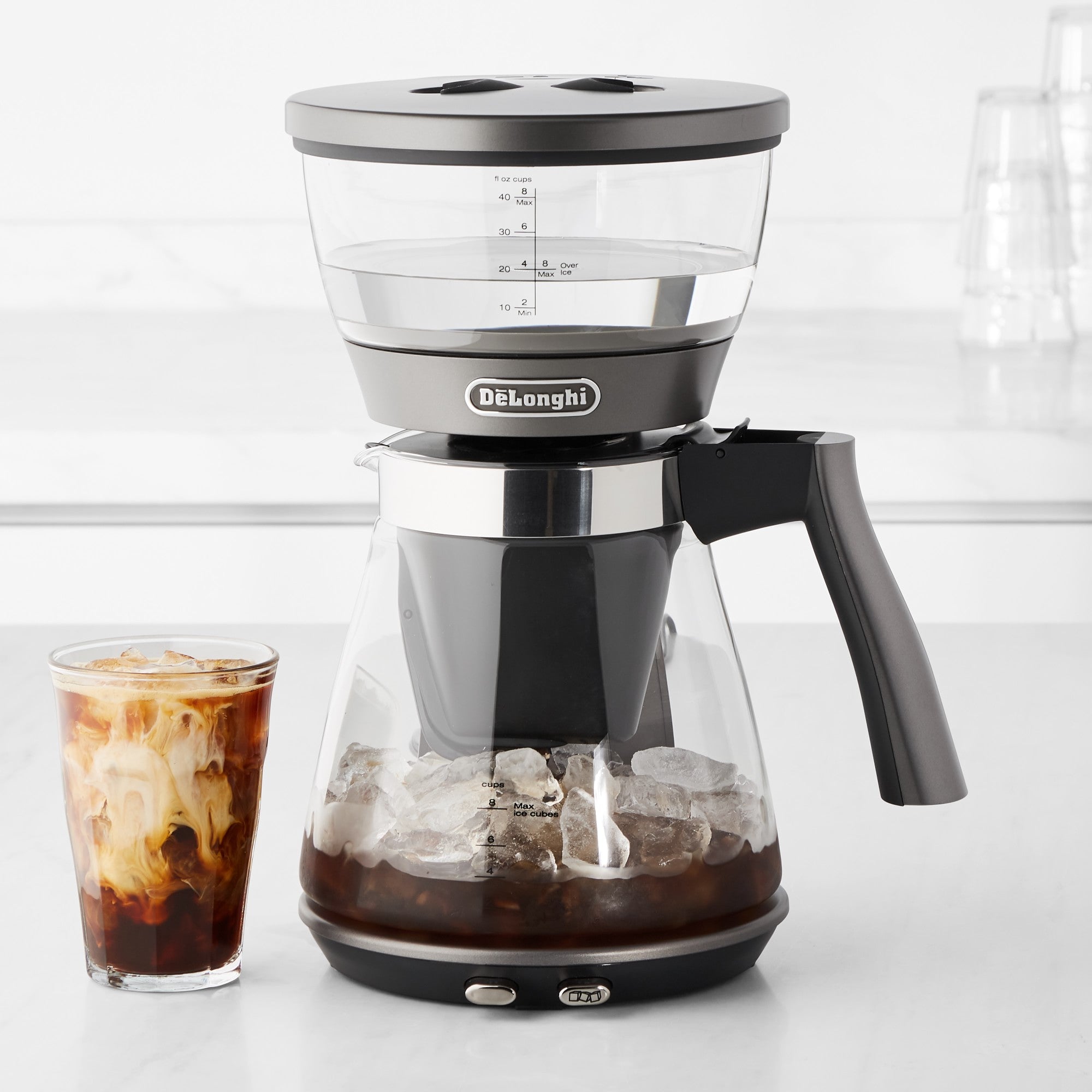De'Longhi iced coffee maker with clear chamber, black handle, and measuring scale