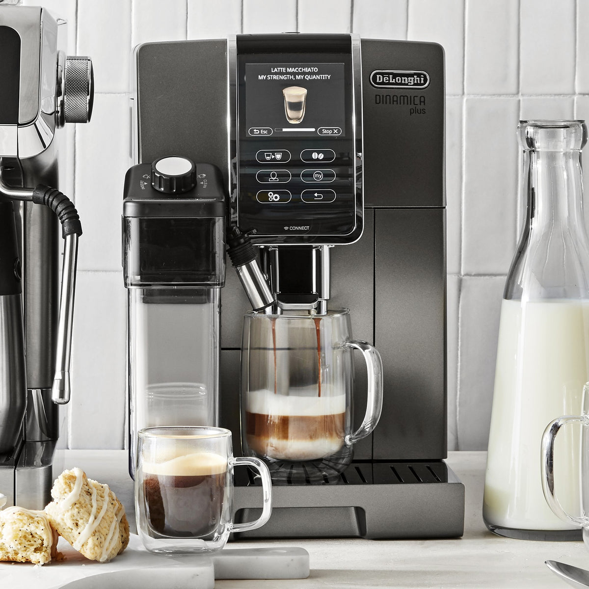 Titanium super-automatic coffee machine dispensing into two cups with a milk carafe