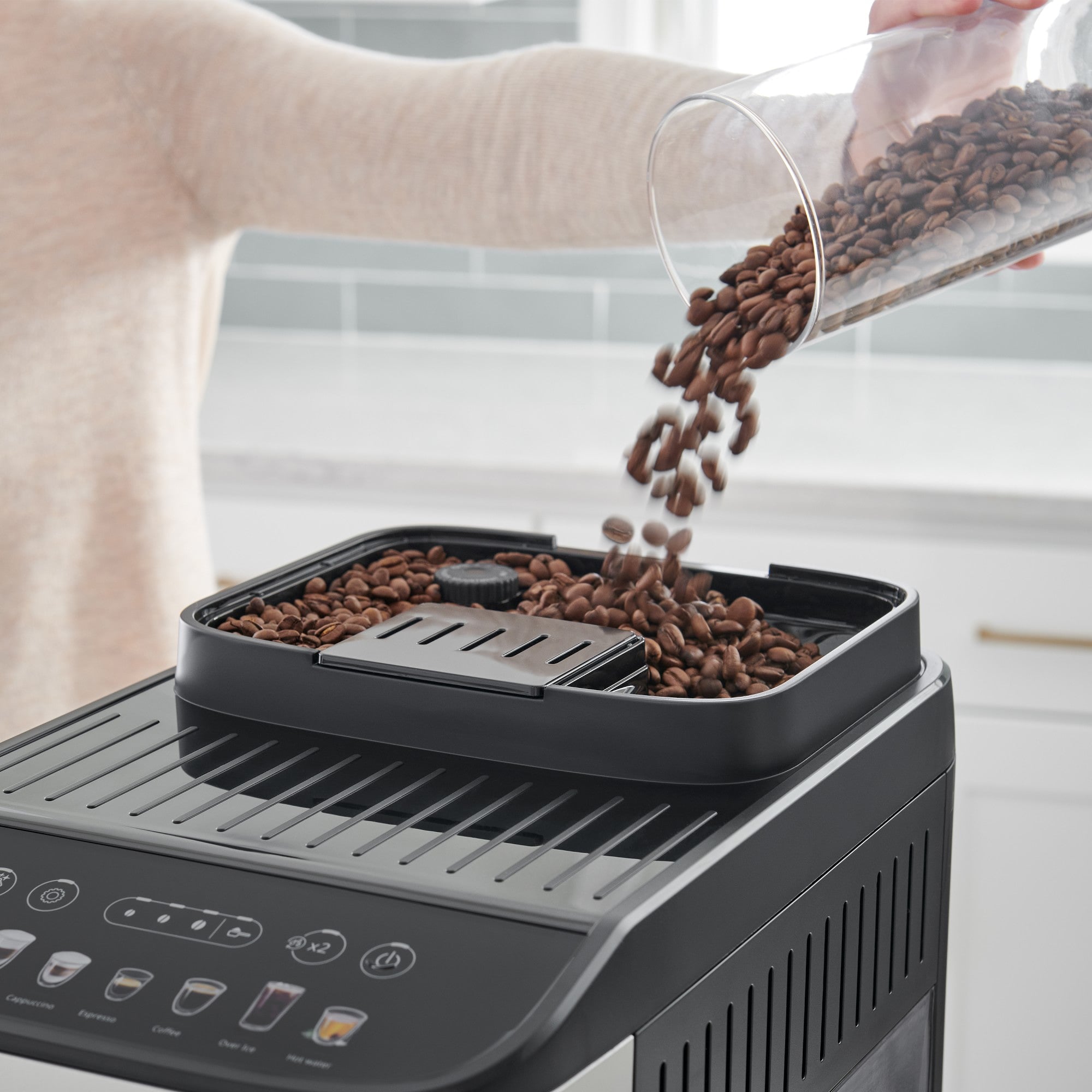 Bean hopper pouring coffee beans into brew tray on De'Longhi Magnifica Evo espresso machine