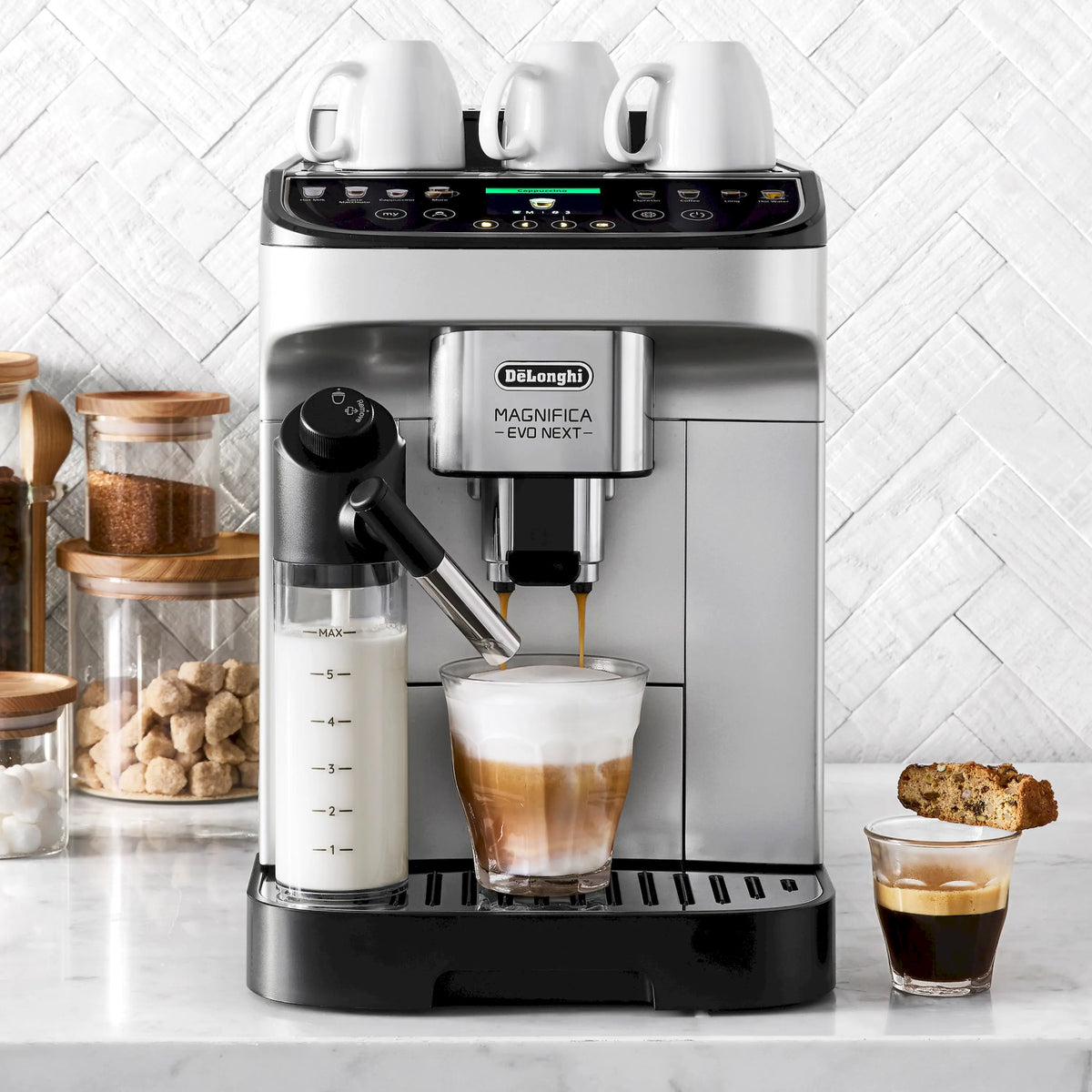 Fully automatic espresso machine with cups and accessories on counter, stainless and black body.