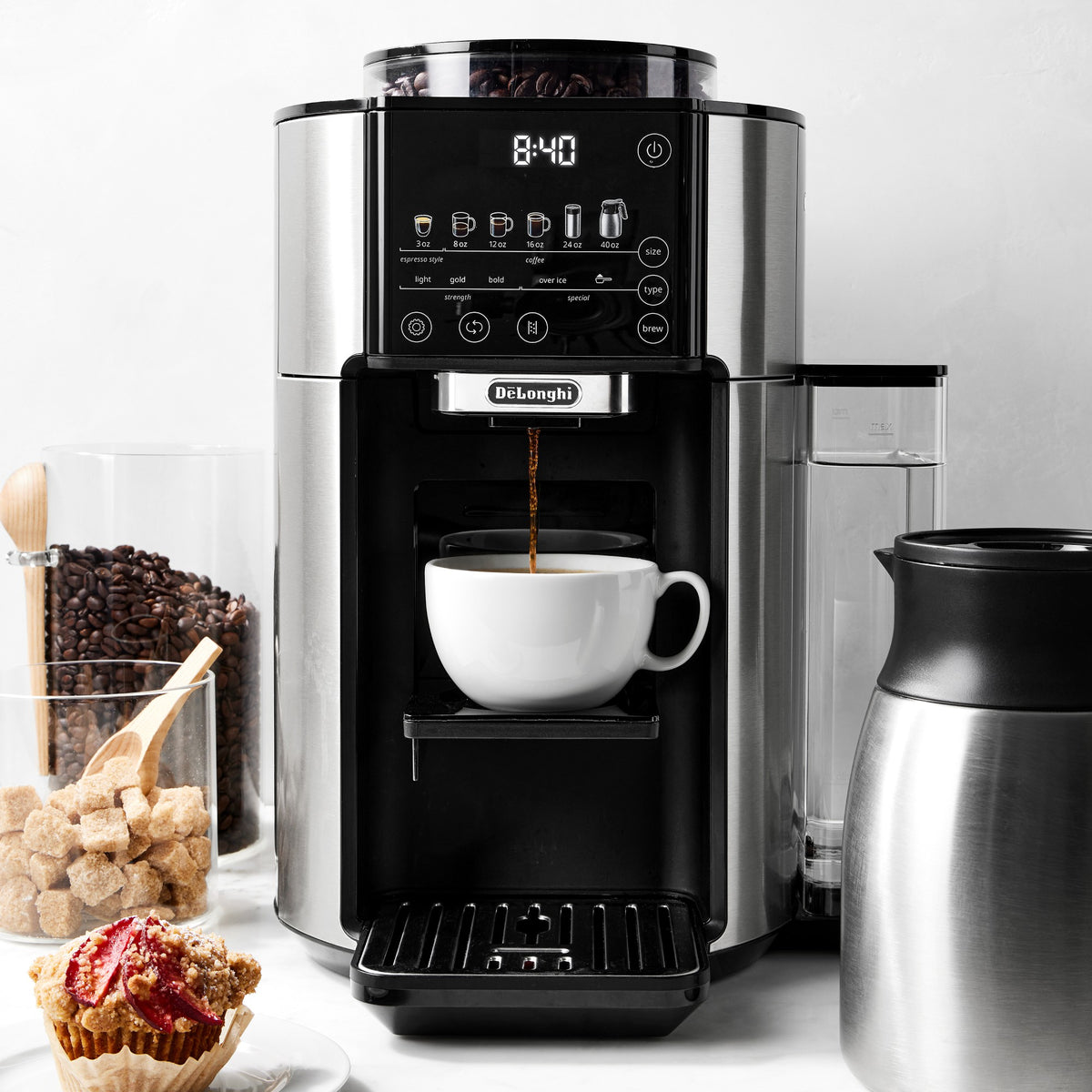 Automatic coffee maker pouring hot coffee into a white mug with glass carafe nearby
