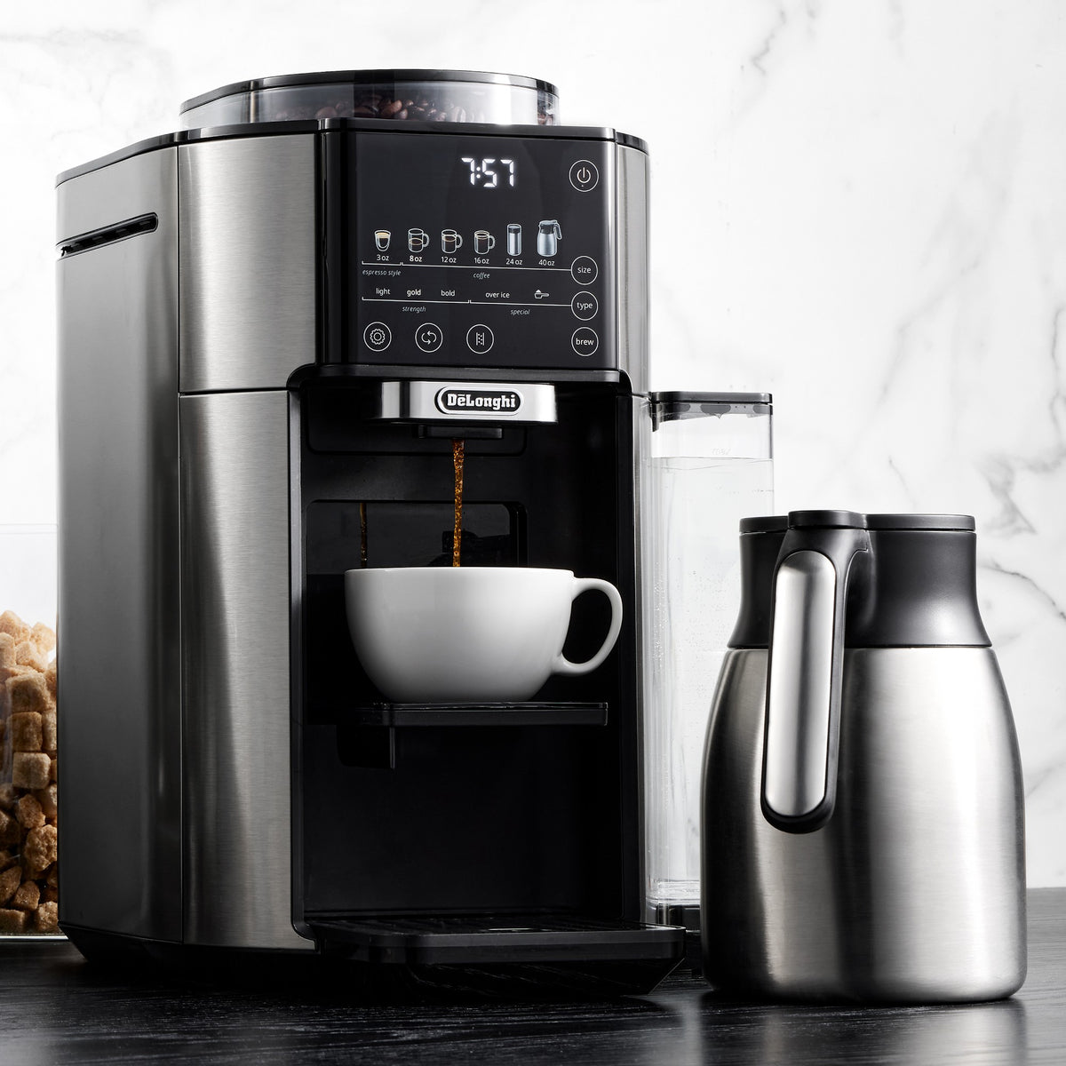 Automatic coffee maker pouring coffee into a white mug with stainless thermal carafe
