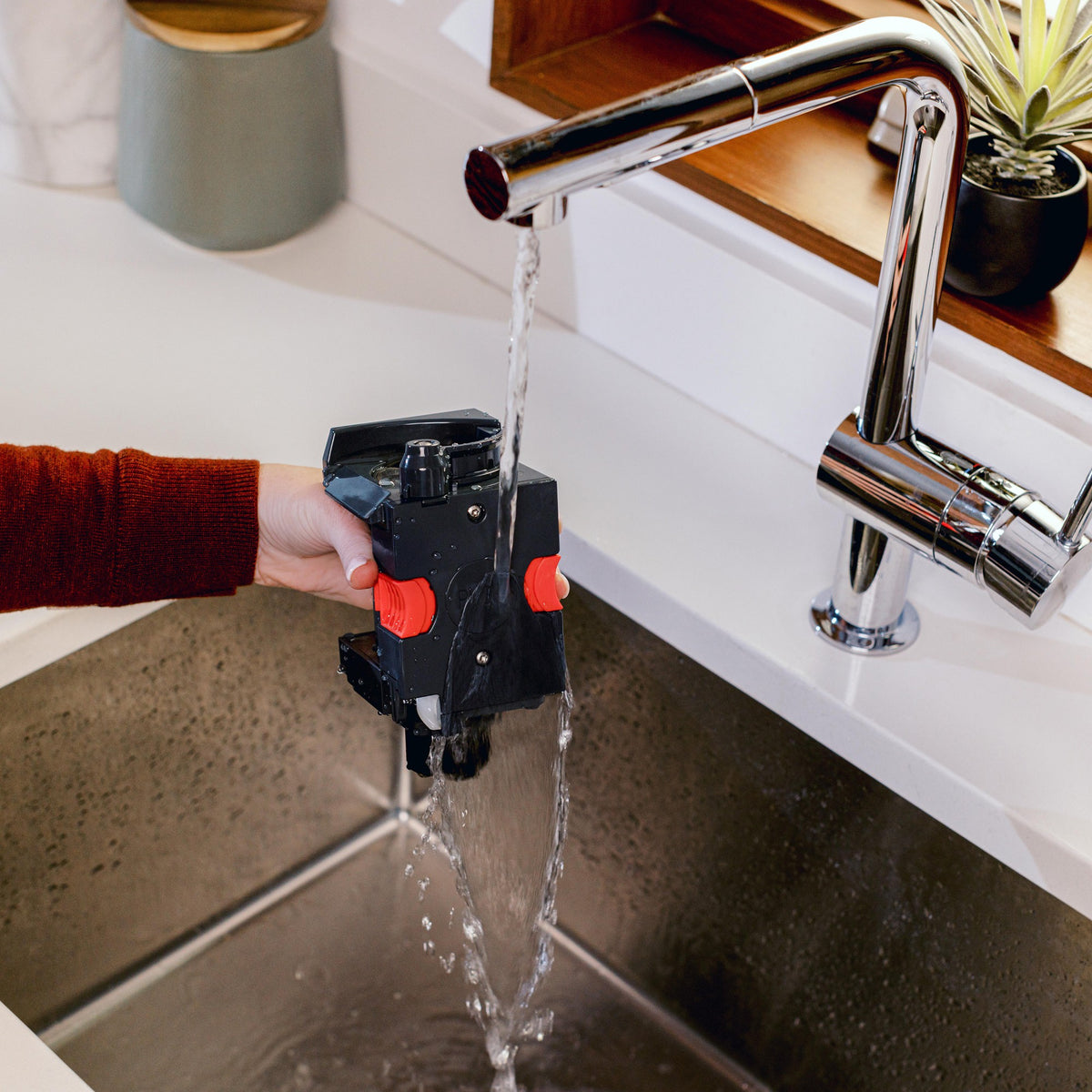 Coffee maker dispenser spout releasing water into a kitchen sink