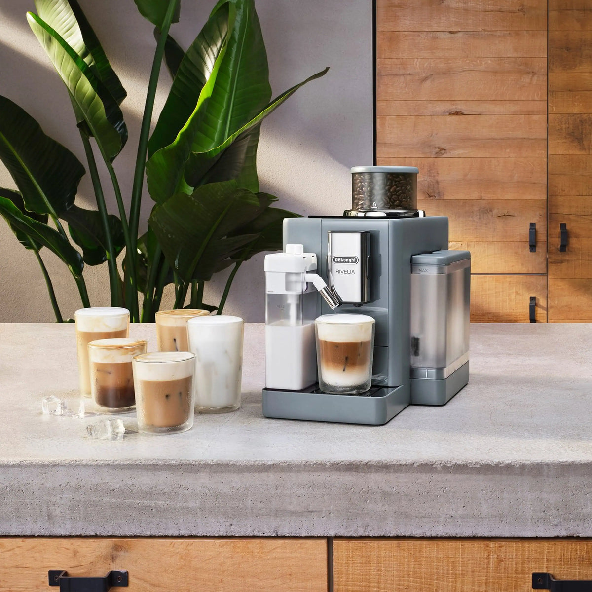 Grey and white coffee machine with carafe and four iced glasses on counter