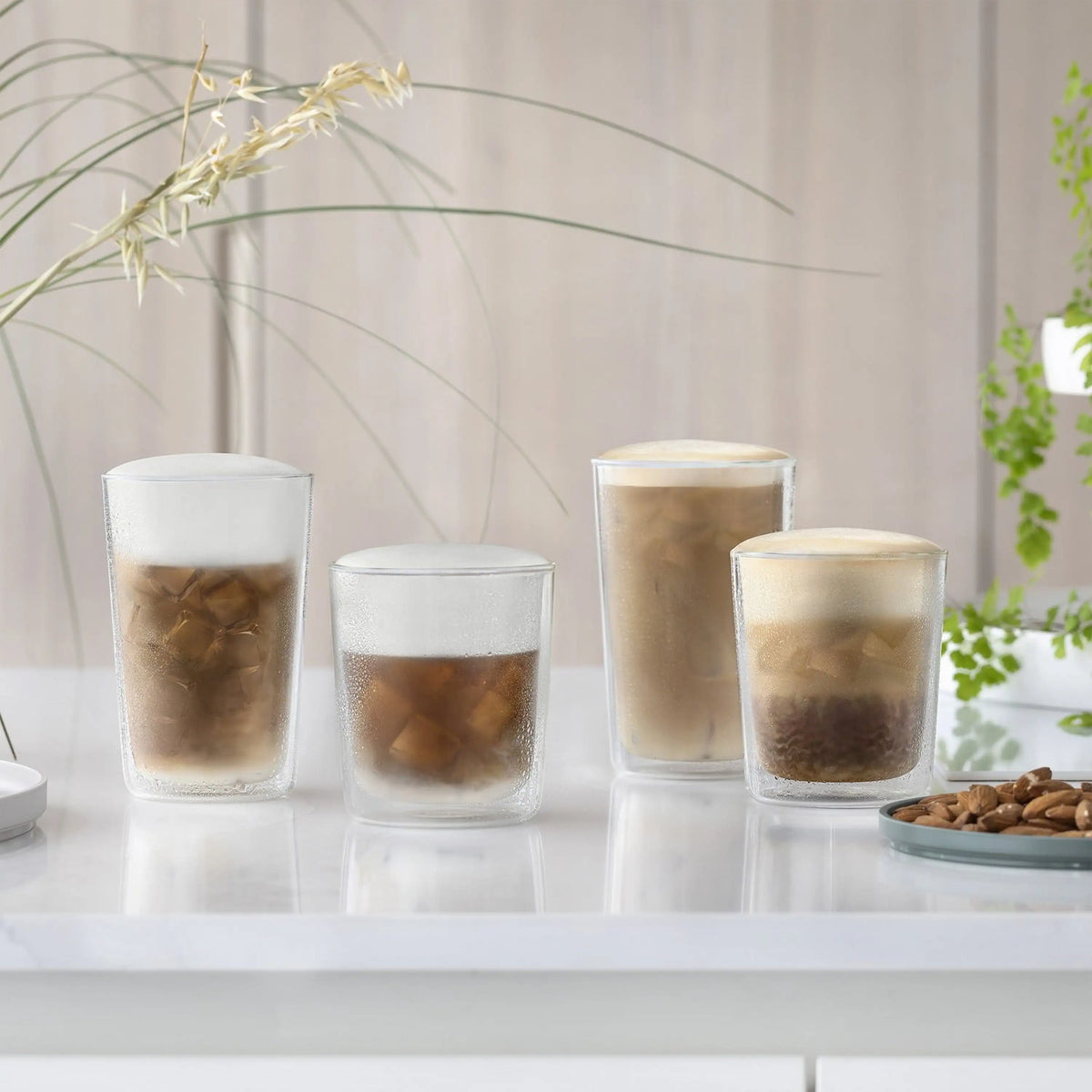 Clear cups with iced coffee foam, arranged on a reflective tray