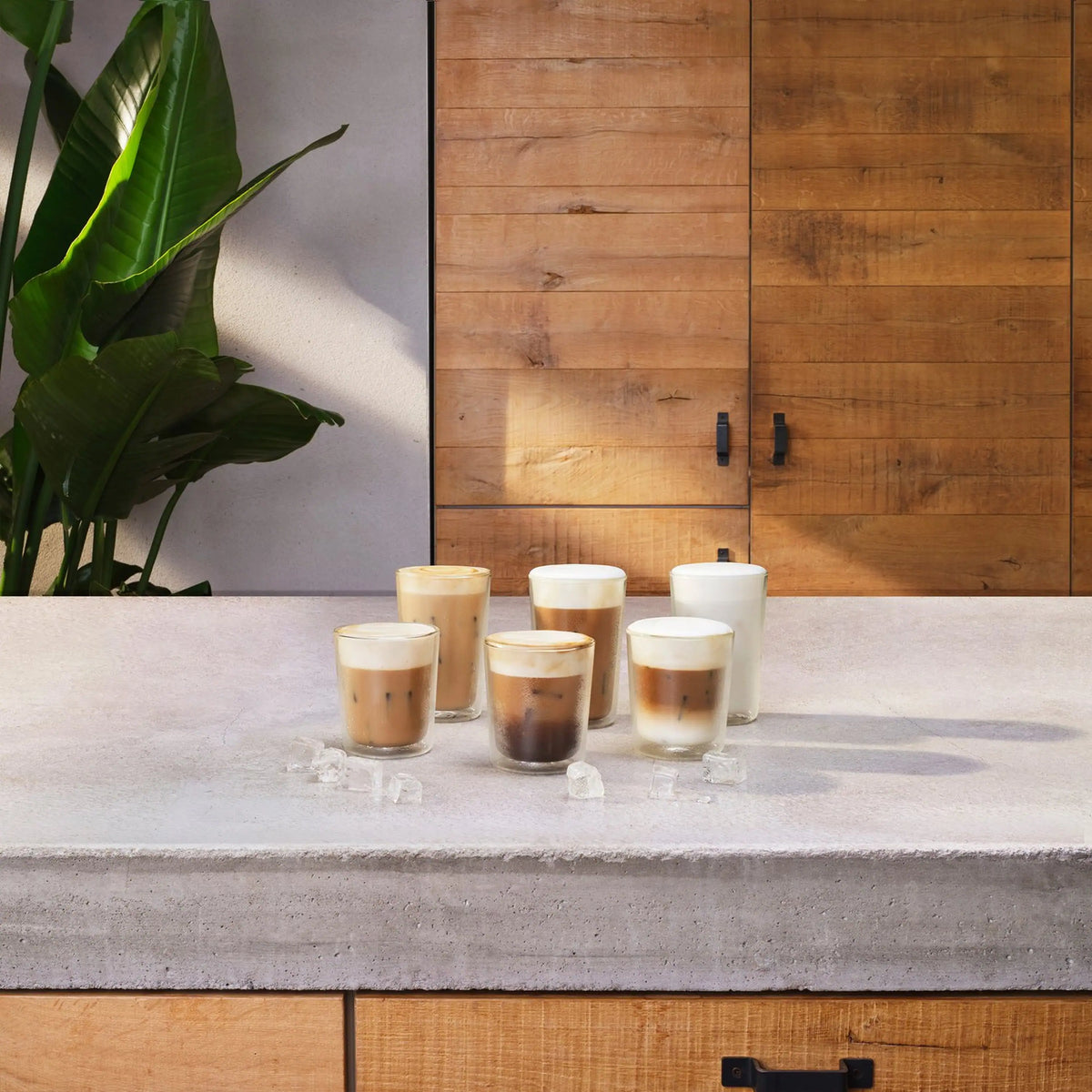White accessory dispensing over multiple clear cups of iced latte on a countertop