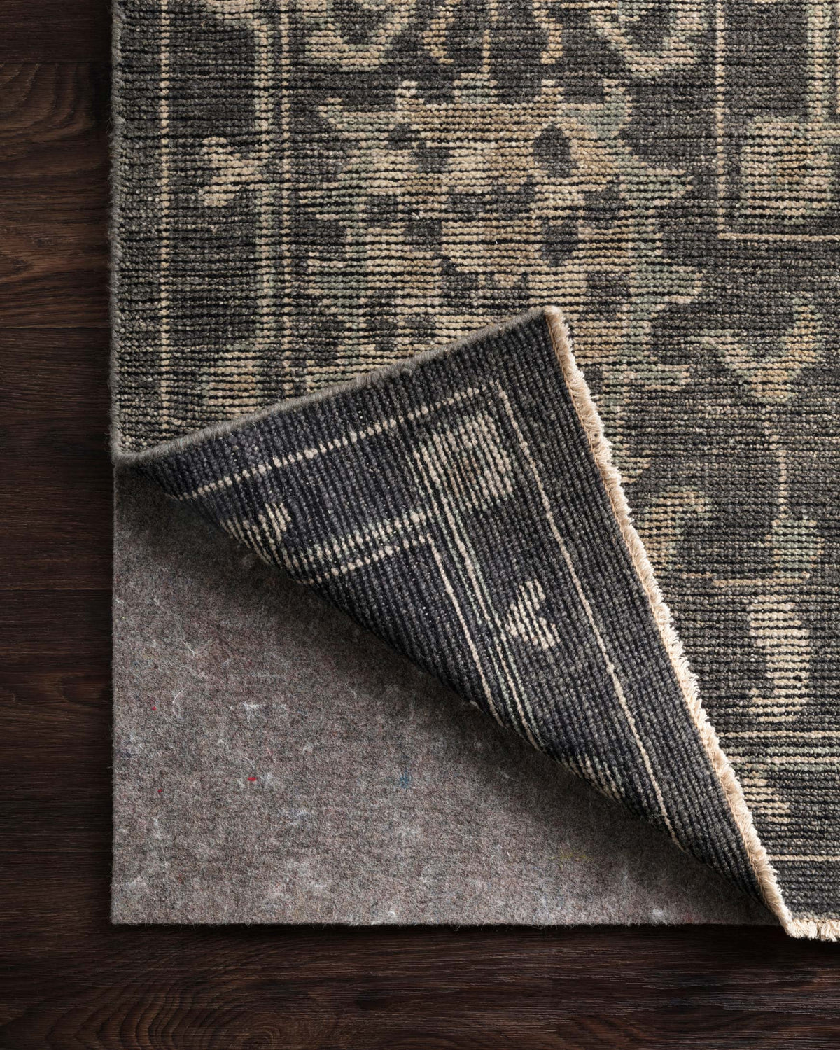 Grey felted area rug with abstract distressed pattern, rolled corner detail