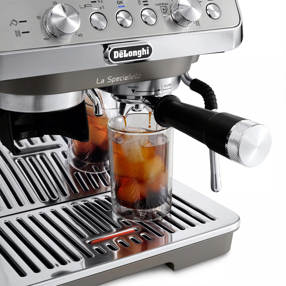 Cold brew cup under black spout on stainless espresso machine drip tray.