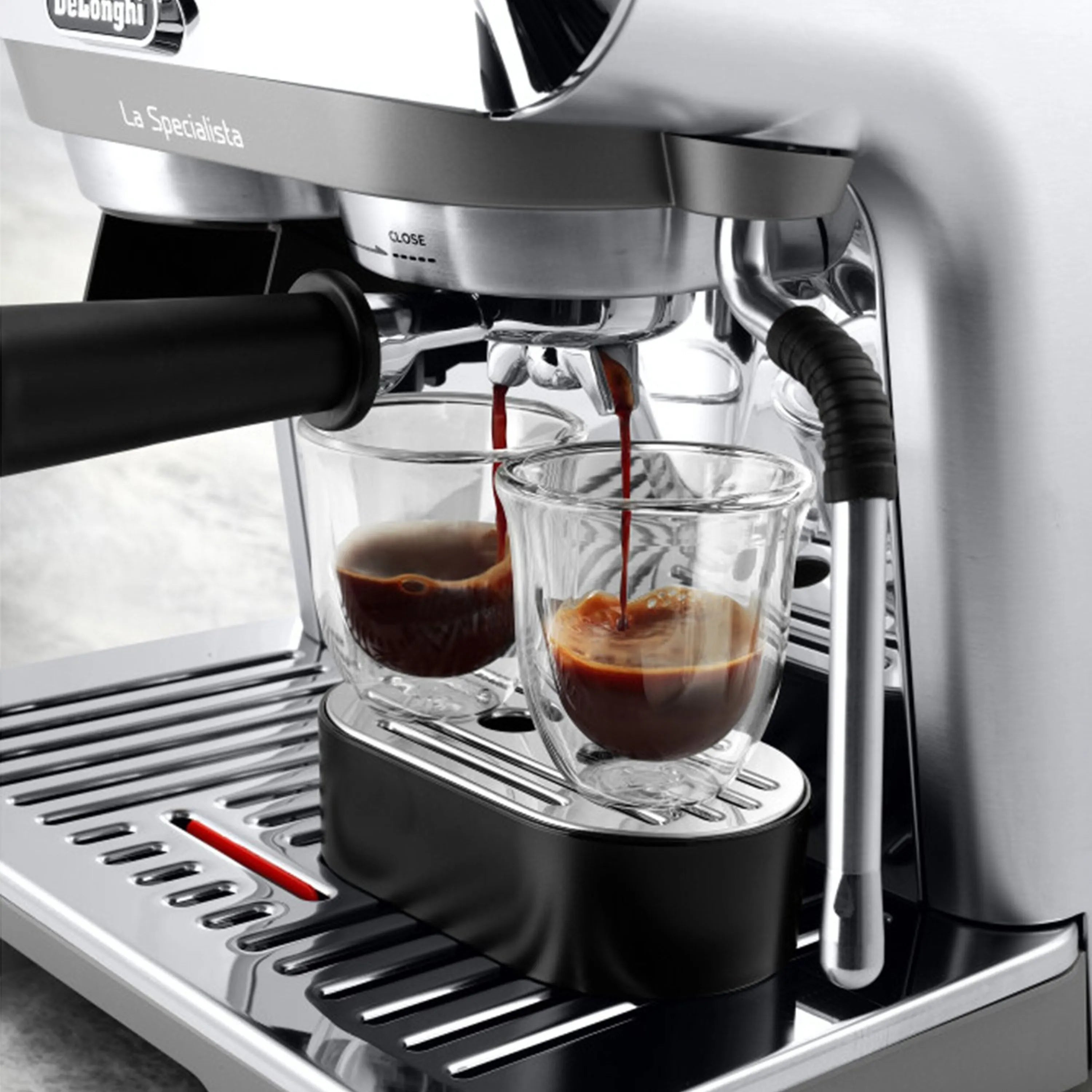 Stainless espresso machine dispensing dark coffee into two glass cups