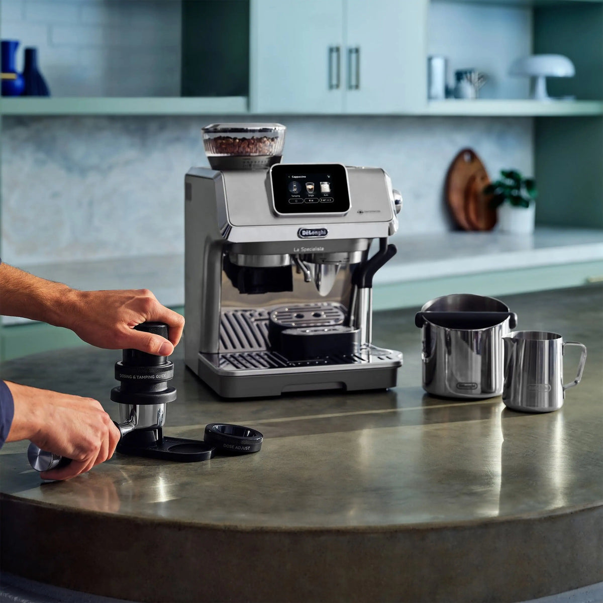 Stainless espresso machine with touch display dispensing into cups; person adjusts handle