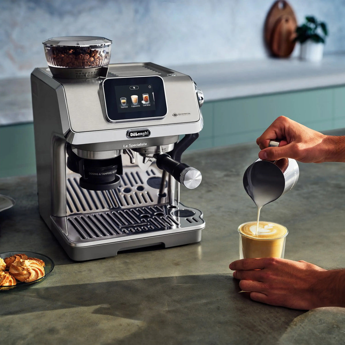 Stainless espresso machine with touch display; hands pour milk into a clear glass