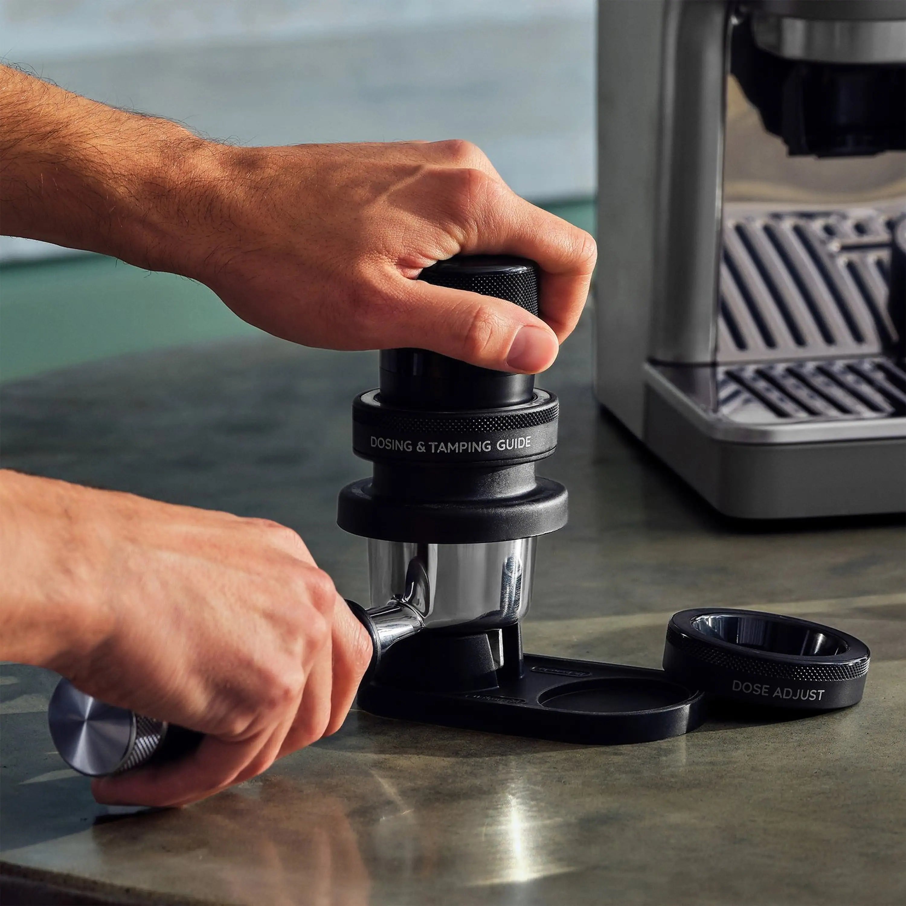 Hands loading portafilter with dosing/tamping guide on espresso machine