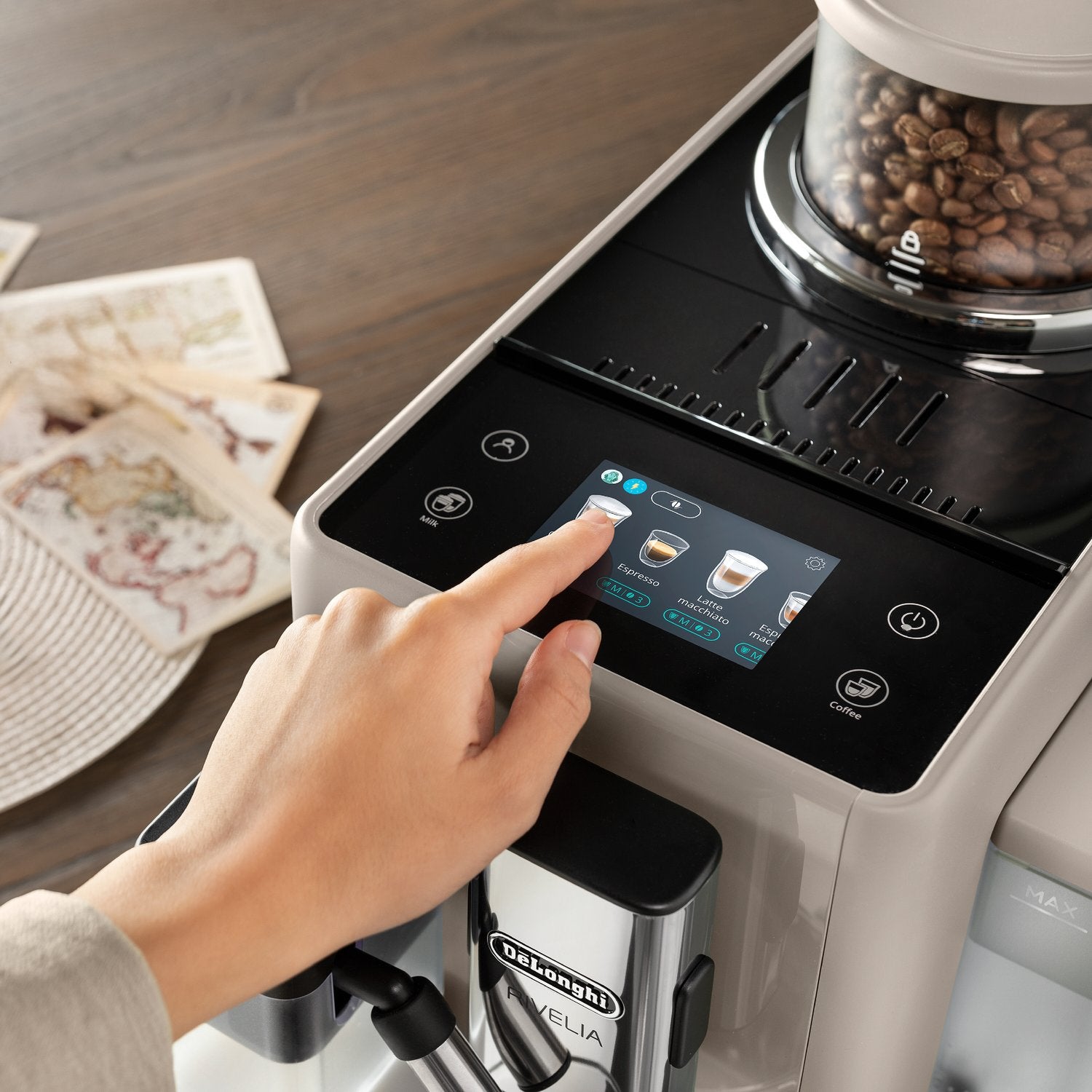 Beige espresso machine with touchscreen control and a hand pressing drink settings