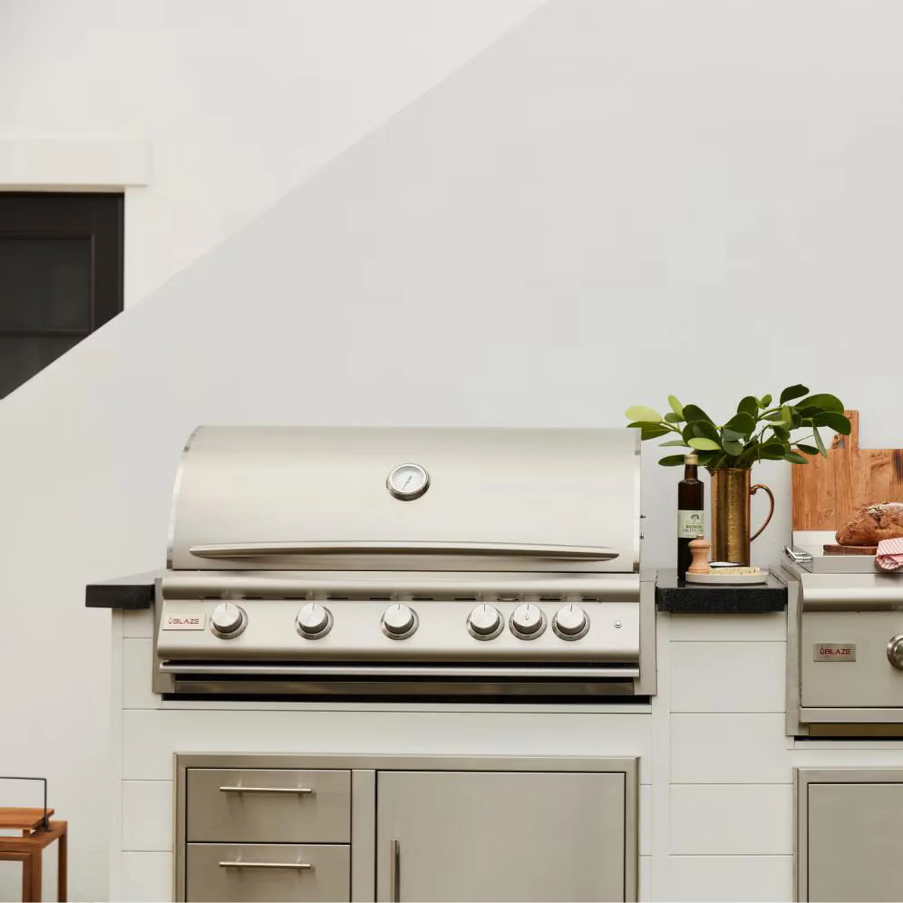 Stainless built-in natural gas grill with closed hood installed in outdoor kitchen