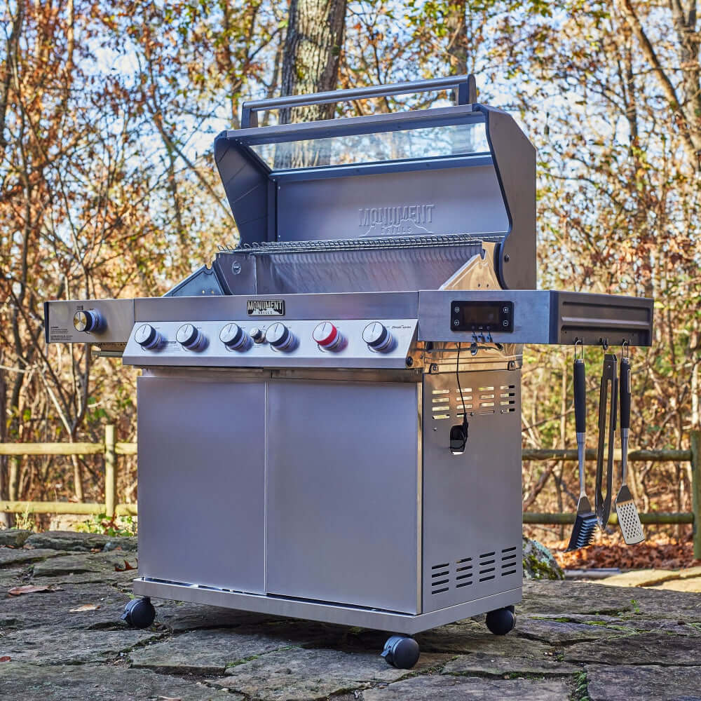 Stainless steel gas grill with open hood, front burner controls, and side cabinet