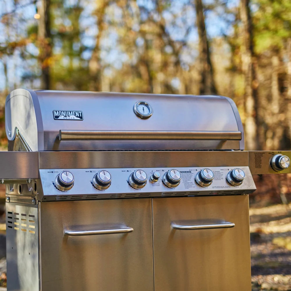 Stainless steel grill control panel with burner knobs and logo on the lid