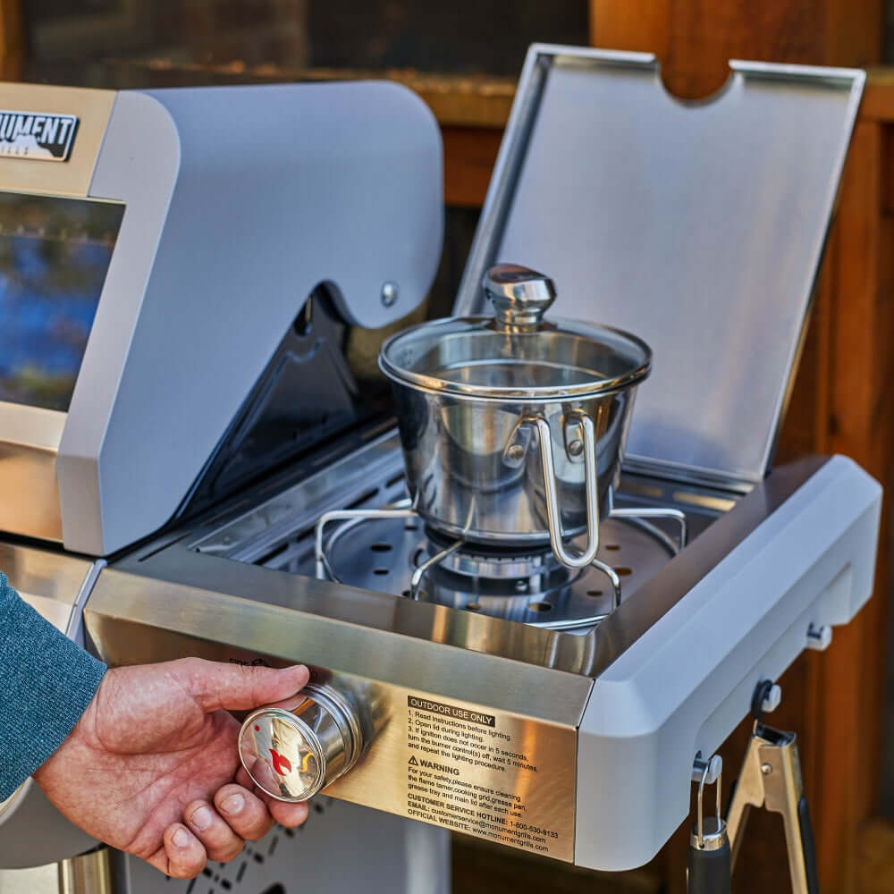Stainless steel grill side burner area with a can being held