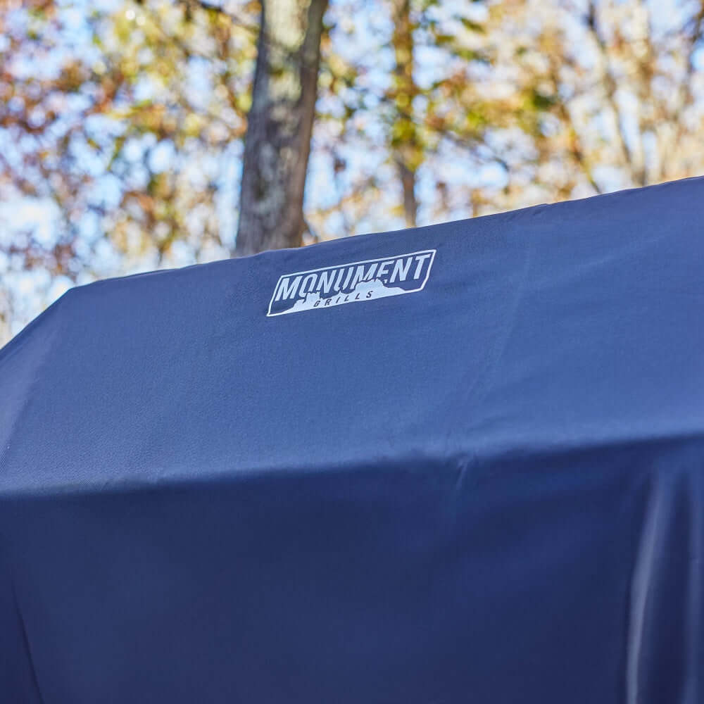 Navy grill cover with Monument Grills logo on the top