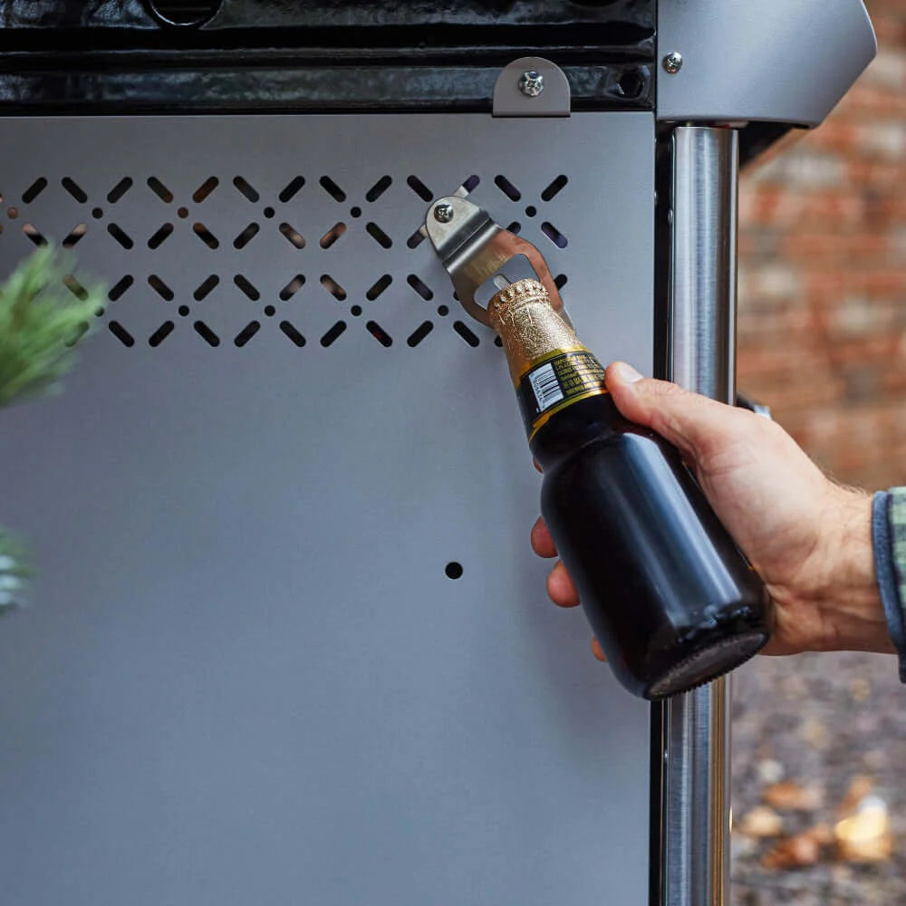 Hand lighting a stainless steel grill burner with a torch-style igniter
