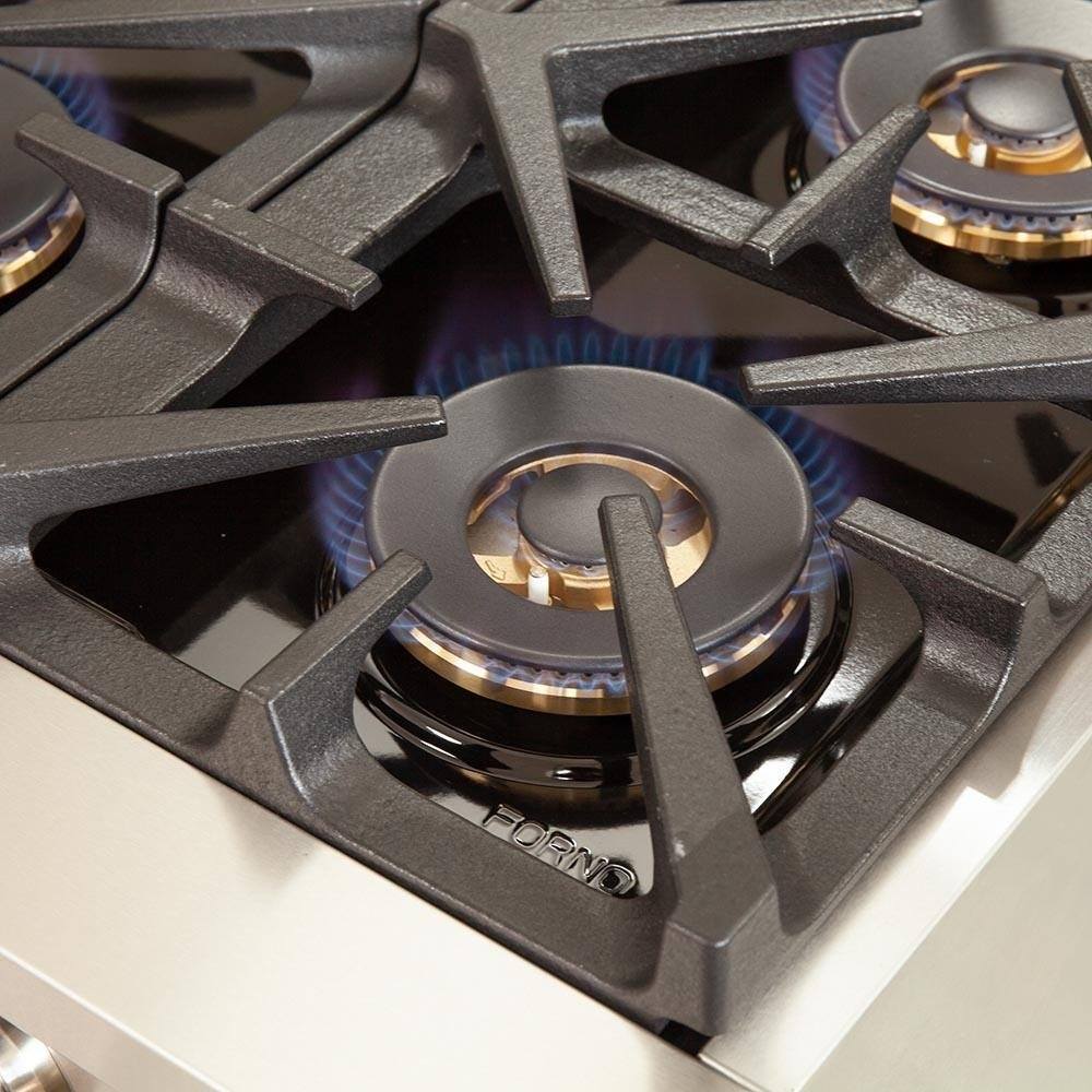 Close-up of gas burner grate and igniter area on stainless steel range top