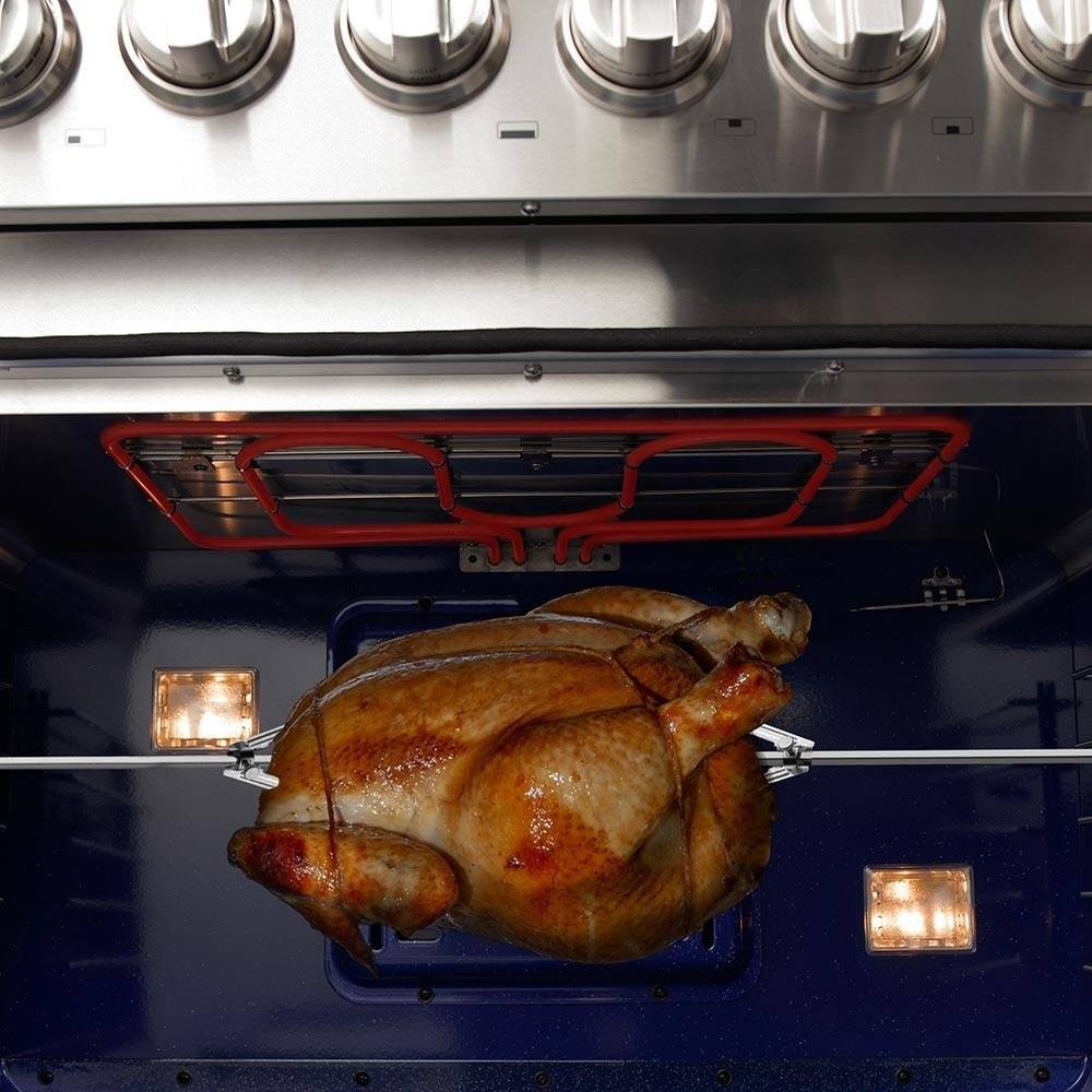 Roasted chicken in a dark oven cavity with interior lights glowing