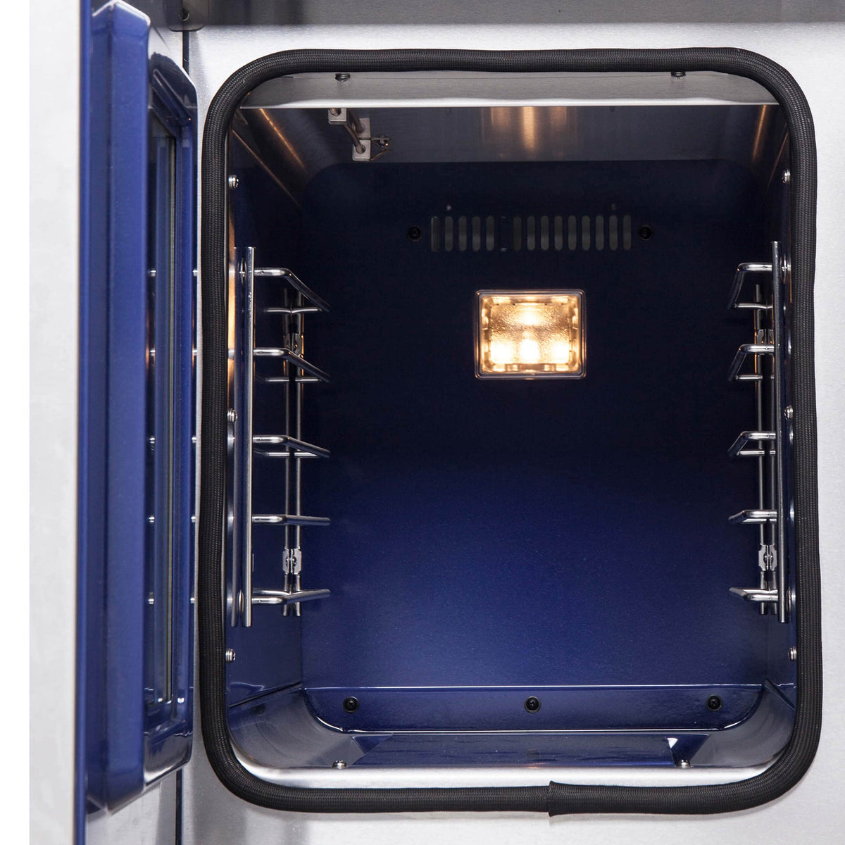 Stainless oven interior with racks, side rails, and oven light on, door open.